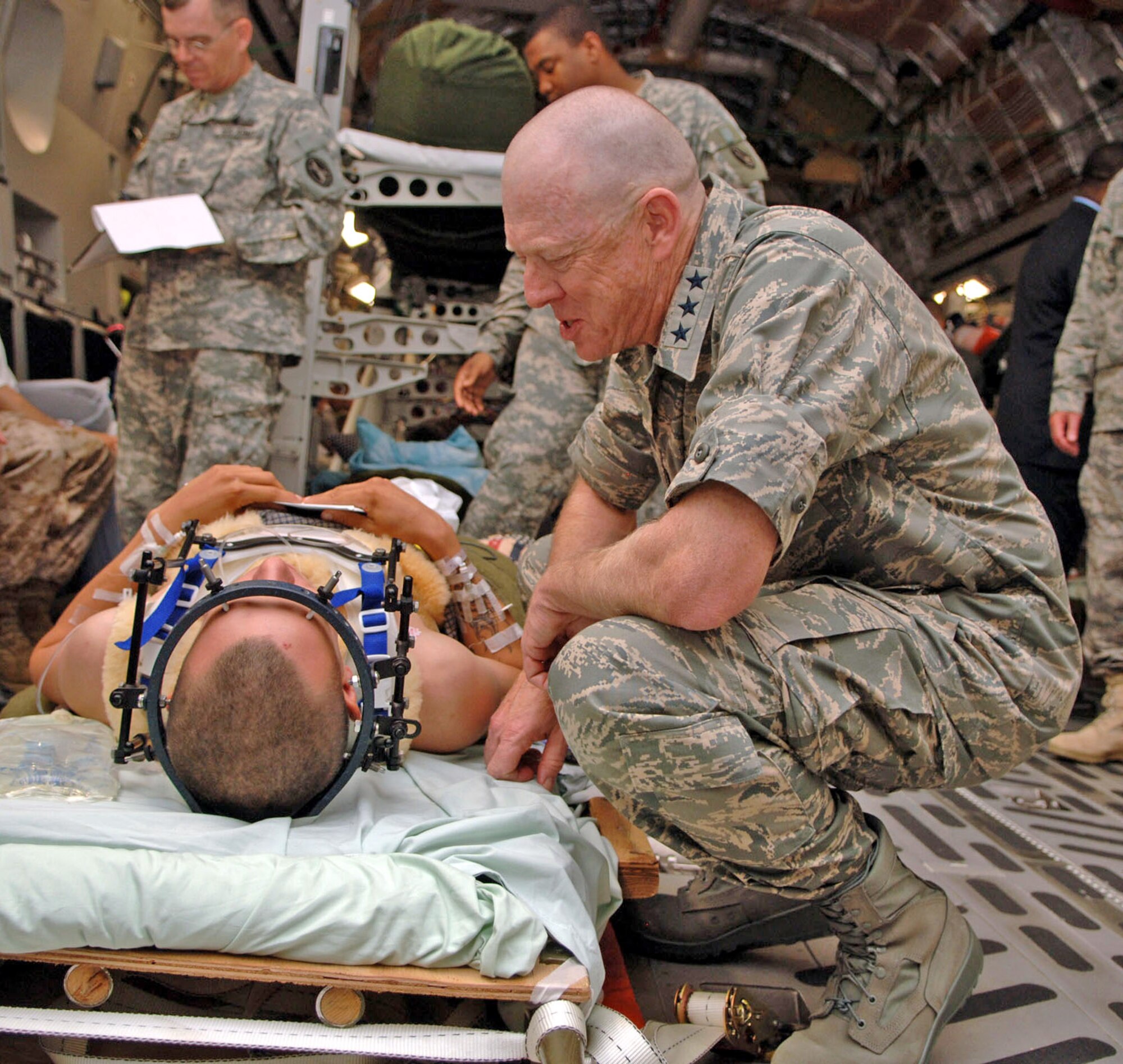 Lt. Gen. (Dr.) James G. Roudebush, Air Force surgeon general, chats with a wounded Soldier returning from overseas during a visit to Malcolm Grow Medical Center's Aeromedical Staging Flight at Andrews Air Force Base, Md., June 26. The Soldier was secured to the litter to ensure no further injury during transport on the C-17 Globemaster III, which was flown by a crew from the Mississippi Air National Guard's 172nd Airlift Wing.  With General Roudebush was Dr. S. Ward Casscells, the new assistant secretary of defense for health affairs. (U.S. Air Force photo/Senior Airman Jeff Andrejcik)