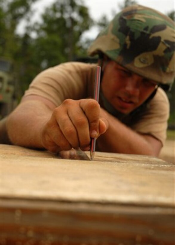 A U.S. Navy sailor from Naval Mobile Construction Battalion 1 draws a cut line on a piece of timber for a timber tower at Camp Shelby, Miss., on June 26, 2007.  The battalion is participating in Operation Desert Heat, a graded field exercise that will assess the battalion's contingency construction capabilities.  