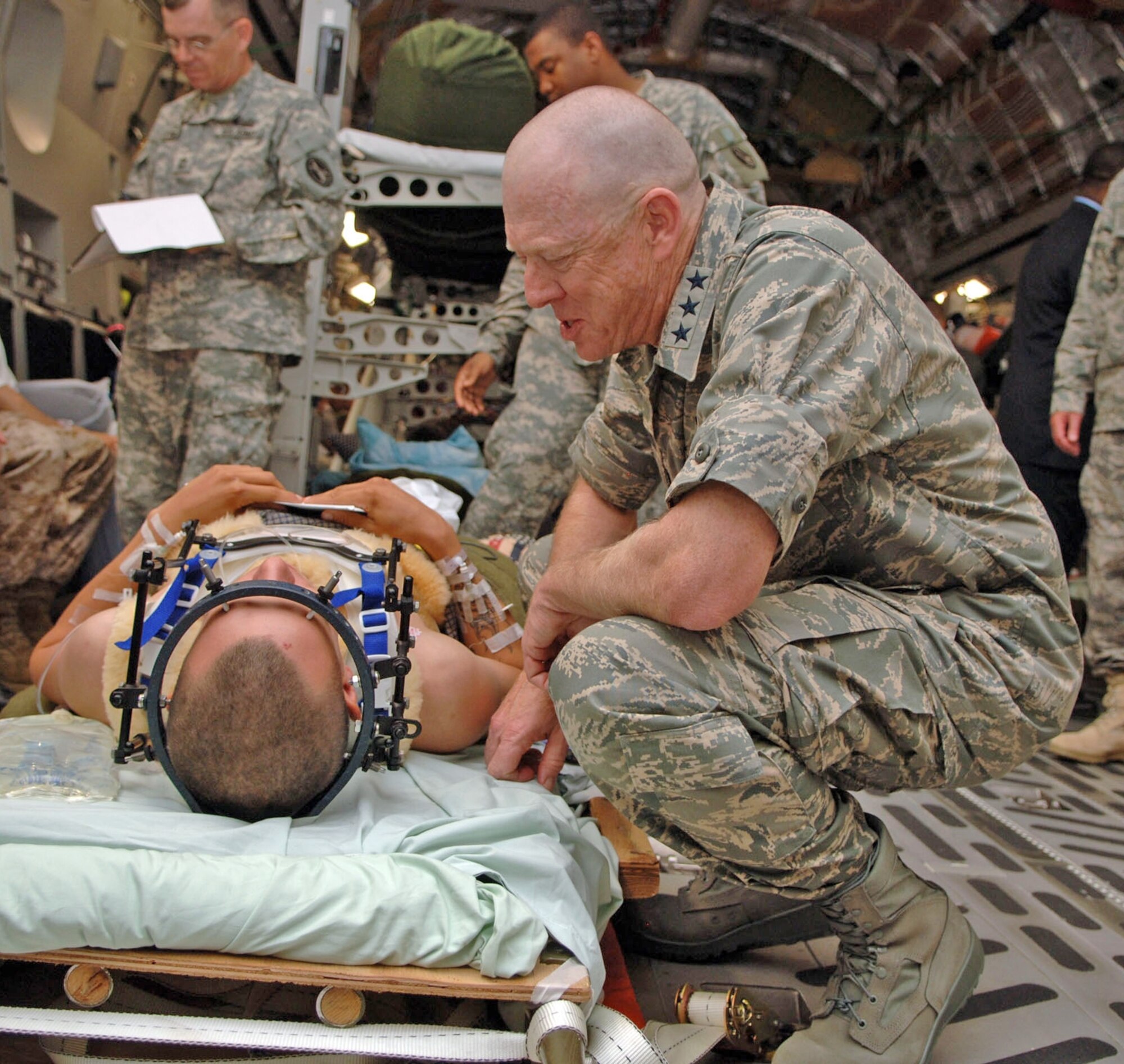 Lt. Gen. (Dr.) James G. Roudebush, Air Force surgeon general, chats with a wounded Soldier returning from overseas during a visit to Malcolm Grow Medical Center’s Aeromedical Staging Flight at Andrews Air Force Base June 26. The soldier was secured to the litter to ensure no further injury during transport on the C-17, which was flown by a crew from the 172nd Airlift Wing of the Mississippi Air National Guard. With General Roudebush was Dr. S. Ward Casscells, the new assistant secretary of defense for health affairs. (U.S. Air Force photo by Senior Airman Jeff Andrejcik)