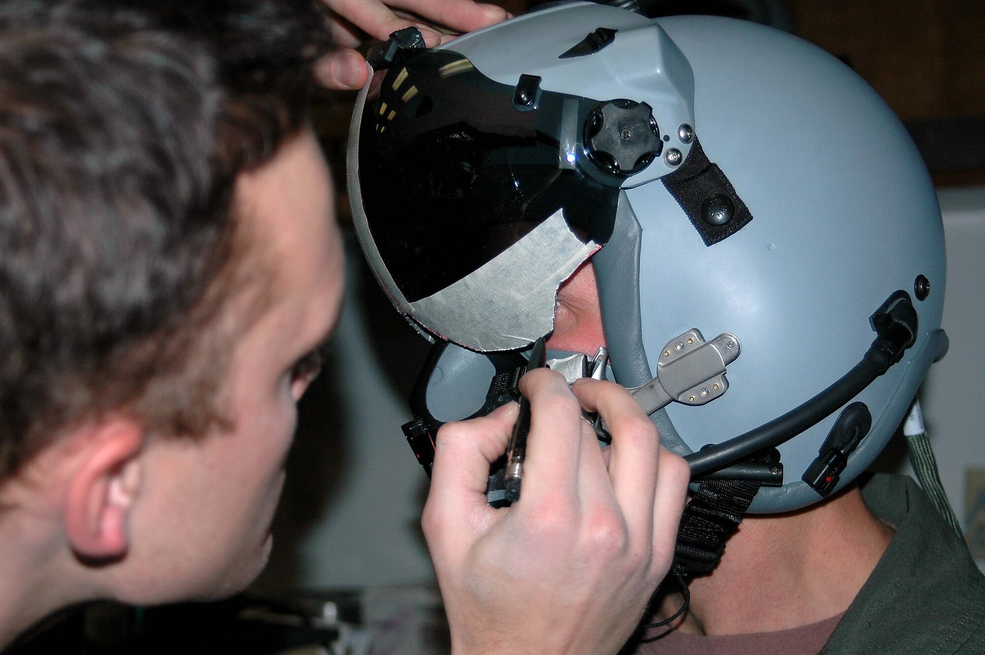 Capt. Lee Dewald, 4th Fighter Squadron pilot, gets an individual fit for his new helmet to fly with the CCIP jets. Senior Airman Mark Fredrickson pencils in around the edges to accurately measure where the visor should be shaved off in order to get a perfict fit.
