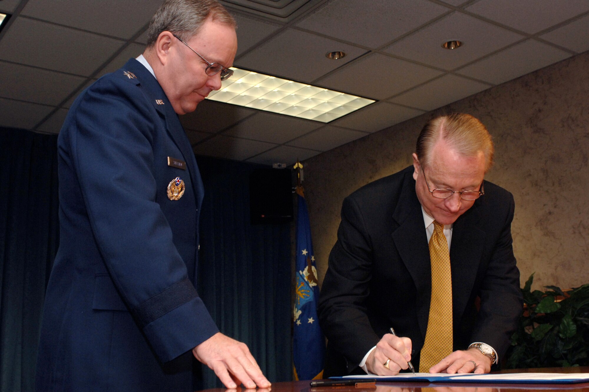 Maj. Gen. Kevin Sullivan, Ogden Air Logistics Center commander, watches as Dr. Richard Kendell, with the commission for the Utah System of Higher Education, takes his turn signing the Education and Training Alliance memorandum here Monday.