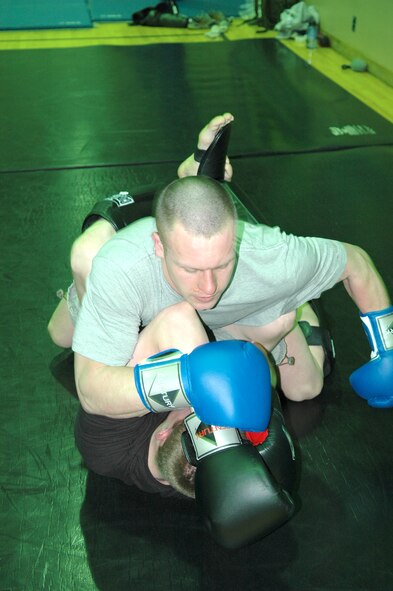FAIRCHILD AIR FORCE BASE, Wash. -- Airman 1st Class Justin Reiter, a Survival, Evasion, Resistance and Escape resistance training instructor, holds down Airman 1st Class Jacob Chambers, SERE specialist, both with the 22nd Training Squadron, during Mixed Martial Arts training Wednesday at the SERE gymnasium. The two are taking part in 30-second ground-and-pound burners, in which the person on the ground is in the guard or defensive position while the other tries to pound away. (Photo by Staff Sgt. Larry Carpenter)
