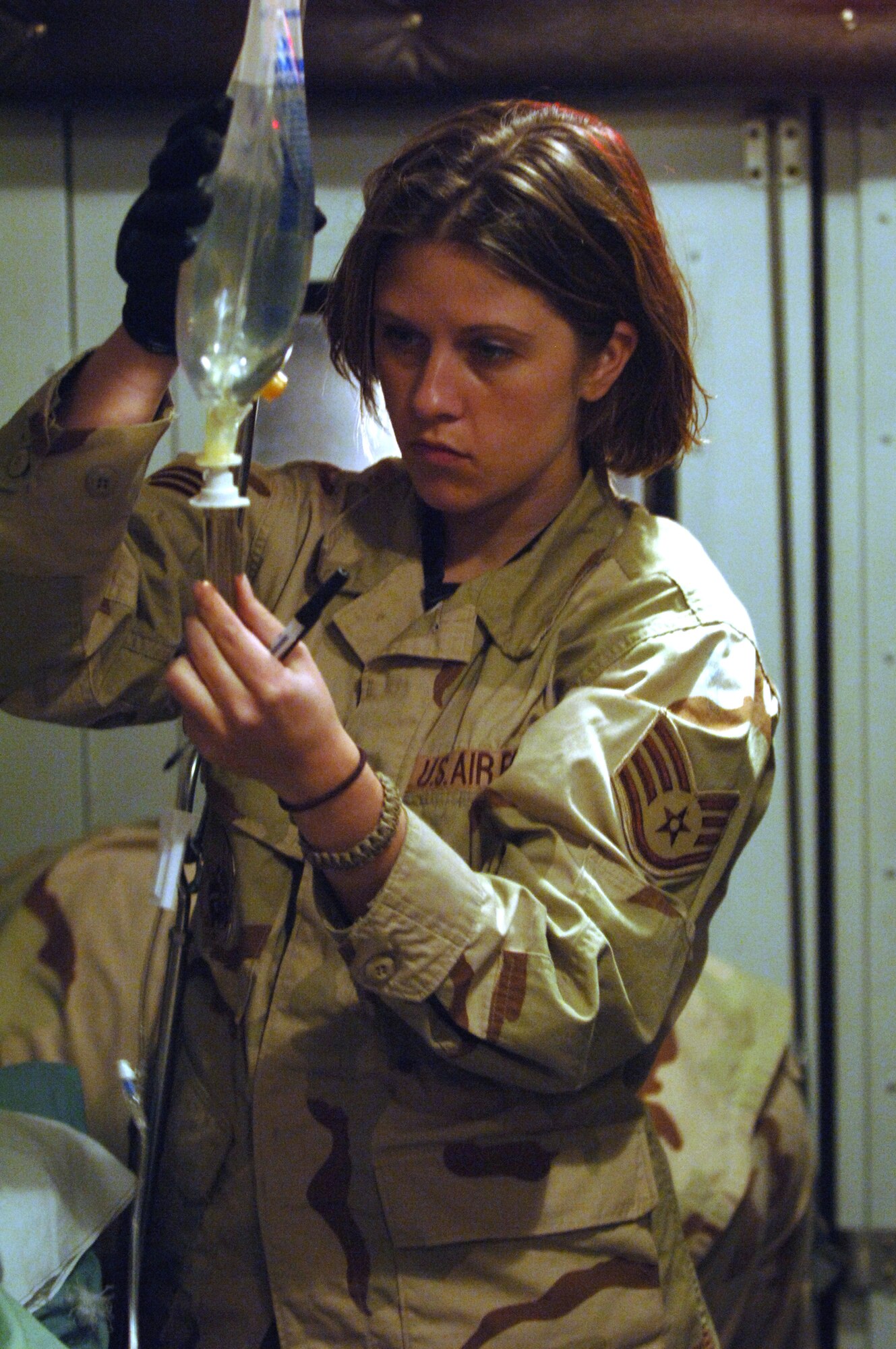 Staff Sgt. Katie Hagemeier checks the intervenes fluids for a patient on a medical transport bus Feb. 21 at Balad Air Base, Iraq, bound for Landstuhl, Germany, where patients receive further care for their wounds. Sergeant Hagemeir is assigned to the 332nd Medical Group Contingency Aeromedical Staging Facility. (U. S. Air Force photo/Staff Sgt. Michael R. Holzworth)
