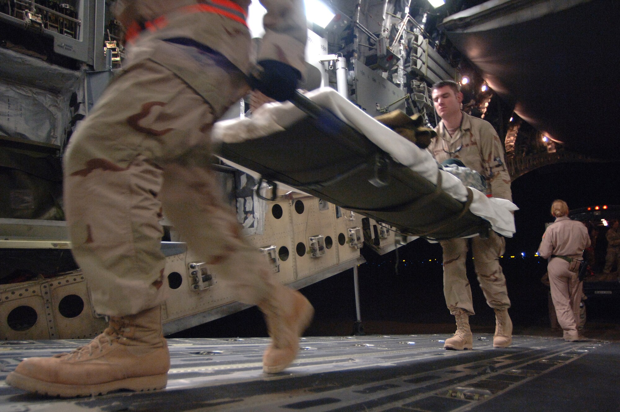 Tech. Sgt. Sean Devine and Senior Airman Ricardo Reveles help load injured Soldiers onto a medical evacuation C-17 Globemaster III Feb. 21 at Balad Air Base, Iraq, departing for Landstuhl, Germany, where they will receive further care for their wounds. Sergeant Devine and Airman Reveles are assigned to the 332nd Expeditionary Communications Squadron and volunteer at the Contingency Aeromedical Staging Facility. (U. S. Air Force photo/Staff Sgt. Michael R. Holzworth) 