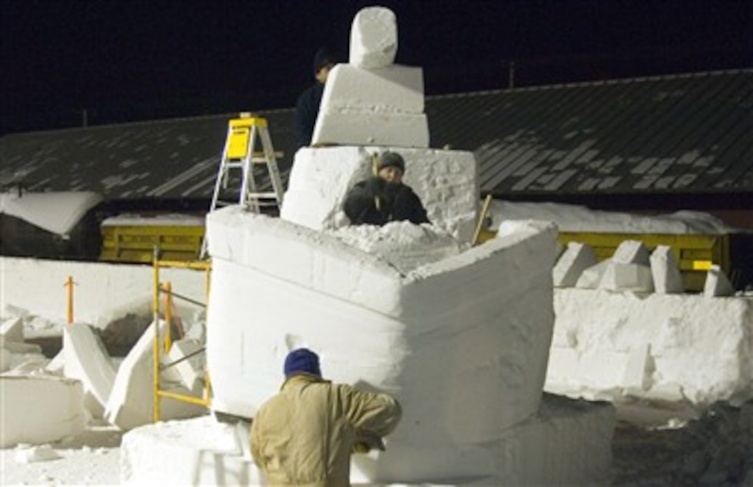 Eric Zimmerman (kneeling), Staff Sgt. Edward Tompkins and Mitchell Manzo (on ladder), comprising the Elmendorf Air Force Base snow sculpting team, work late into the night Feb. 23 carving out a pirate ship during the Anchorage, Alaska, Fur Rendezvous snow sculpture competition.