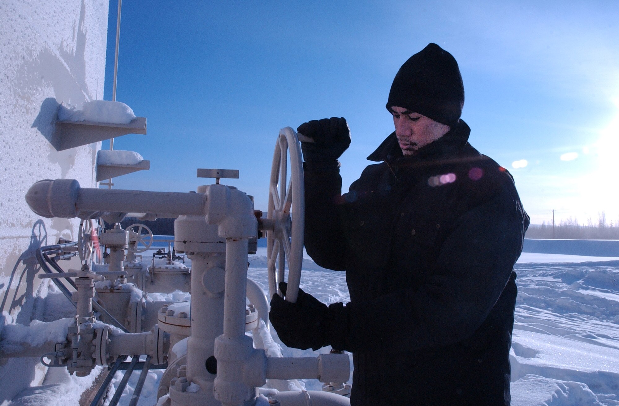 EIELSON AIR FORCE, Alaska -- Airman 1st Class Jeremiah Ulu, 354th Logistics Squadron facilities operator, inspects a fuels valve for leaks and ease of operation. Fighting temperatures as low as minus 60, Airman Ulu performs daily checks on each bulk fuels storage tank. (U.S. Air Force photo by Senior Airman Justin Weaver)  