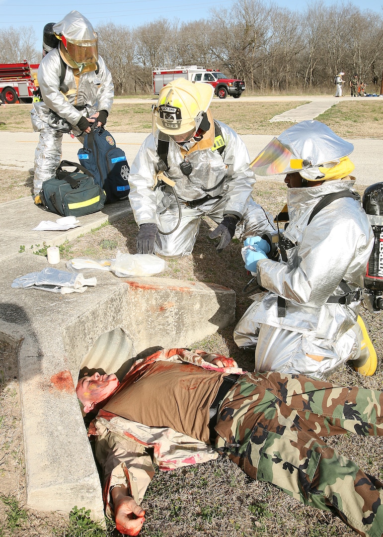 Fire fighters render aid to "injured" Airman Chris Willis, 342nd Training Squadron, during a training exercise at Lackland Air Force Base, Texas, Feb. 26. The 37th Training Wing conducted the mock drill to test and evaluate its ability to respond to a major incident that included reports of explosions and gunfire heard at the Lackland Training Annex. Another scenario involved the hijacking of a C-130 at the Kelly Annex. (USAF photo by Robbin Cresswell)