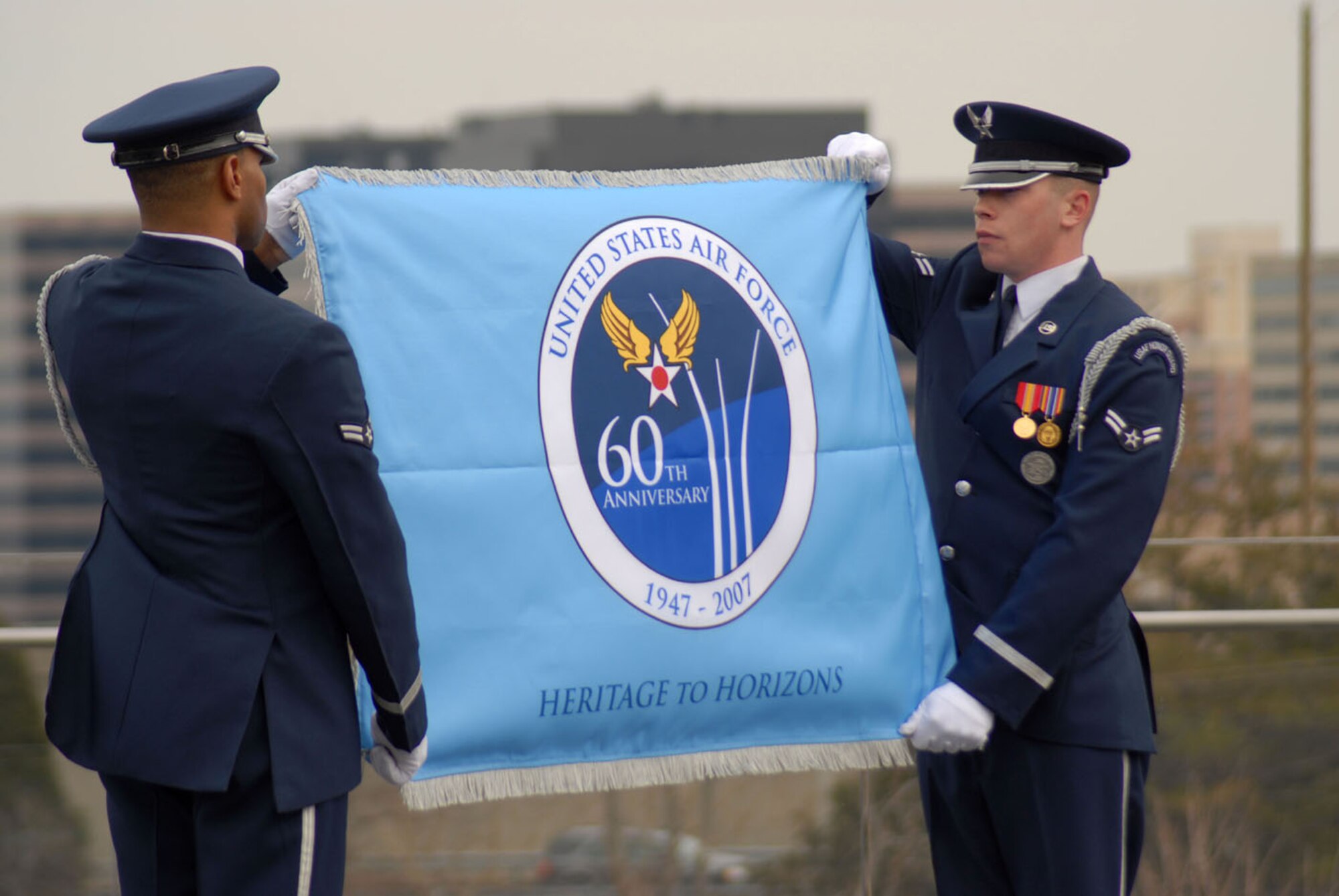 (From left) Airmen 1st Class Ahmad Ware and Brandon Bridges, U.S. Air Force Honor Guard ceremonial guardsmen, unveil the 60th Anniversary Air Force Flag for the first time March 1 at the Air Force Memorial. The ceremony was attended by Chief of Staff of the Air Force Gen. T. Michael Moseley and Secretary of the Air Force Michael Wynn. (U.S. Air Force photo by Staff Sgt. Madelyn Waychoff)