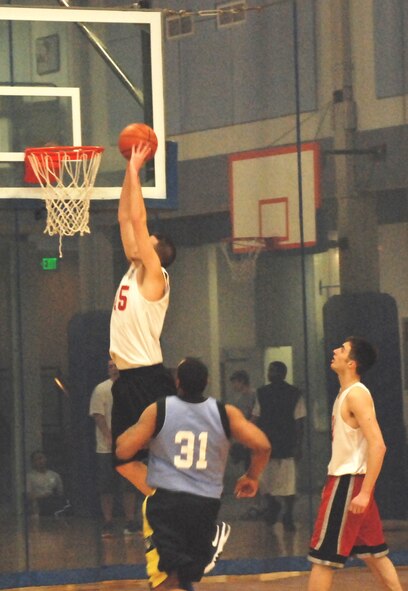 FAIRCHILD AIR FORCE BASE, Wash. -- Mike Perez from the 92nd Services Squadron hammers the ball into the hoop while teammate Zakerry LaFlamme and 92nd Civil Engineer Squadron’s Giovanni Lewis observe during the championship game.  (U.S. Air Force Photo / Staff Sgt. Michael Daniel)