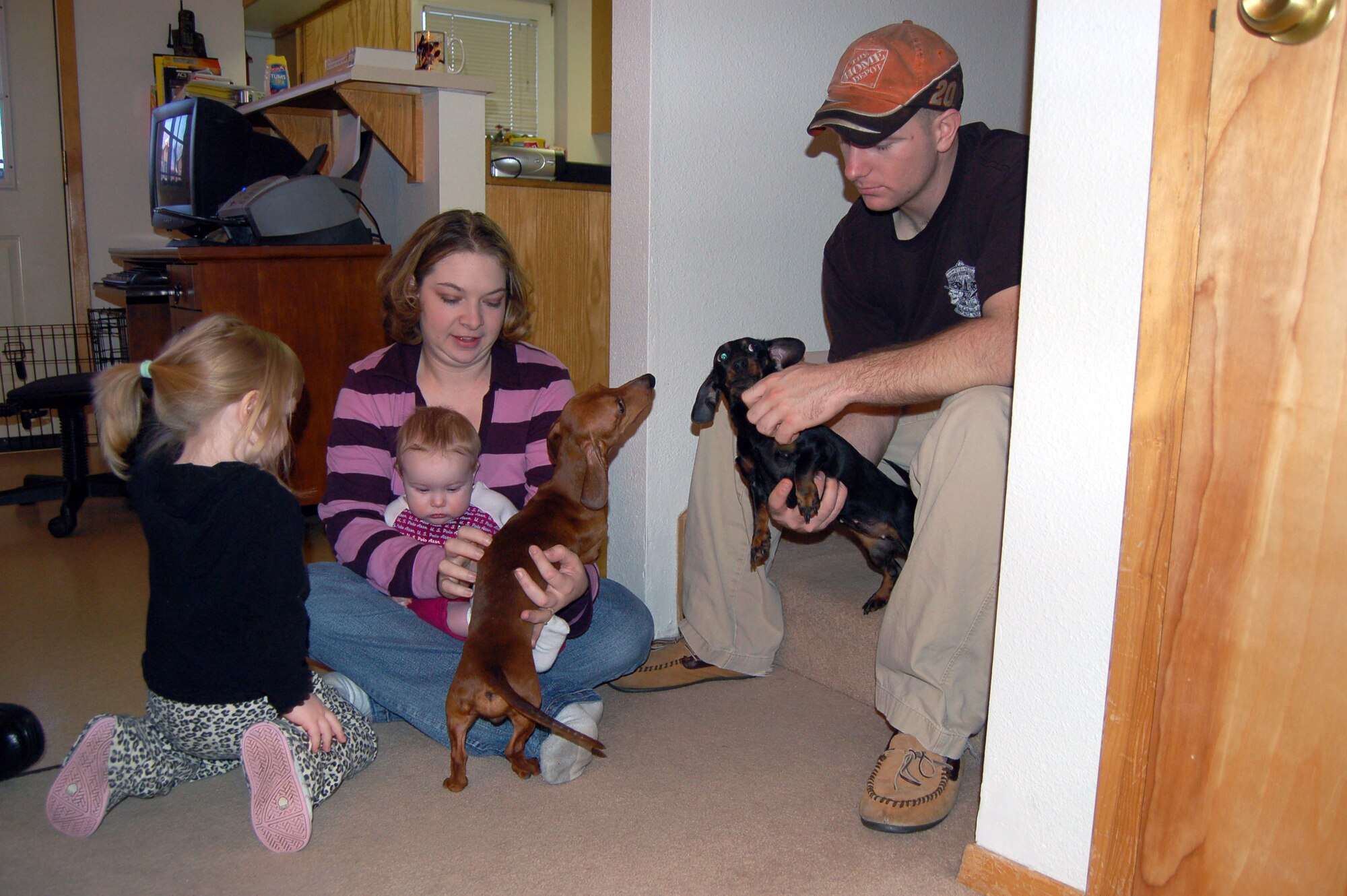 Staff Sgt. Philip Bridges, his wife, Jamie (center), Liberty (left), and 8-month-old Lily, play with their dogs in their new home in base housing Feb. 27 at Eielson Air Force Base, Alaska. They were one of 300 families living in the Sprucewood Homes section of the base's privatized housing. The Bridges and other Air Force families had to be moved out of the privatized housing into new housing from September to December. The reason for the move was due to a conclusion of a privatized housing contract that wasn't able to be renegotiated. (U.S. Air Force photo/Staff Sgt. Matthew Rosine)