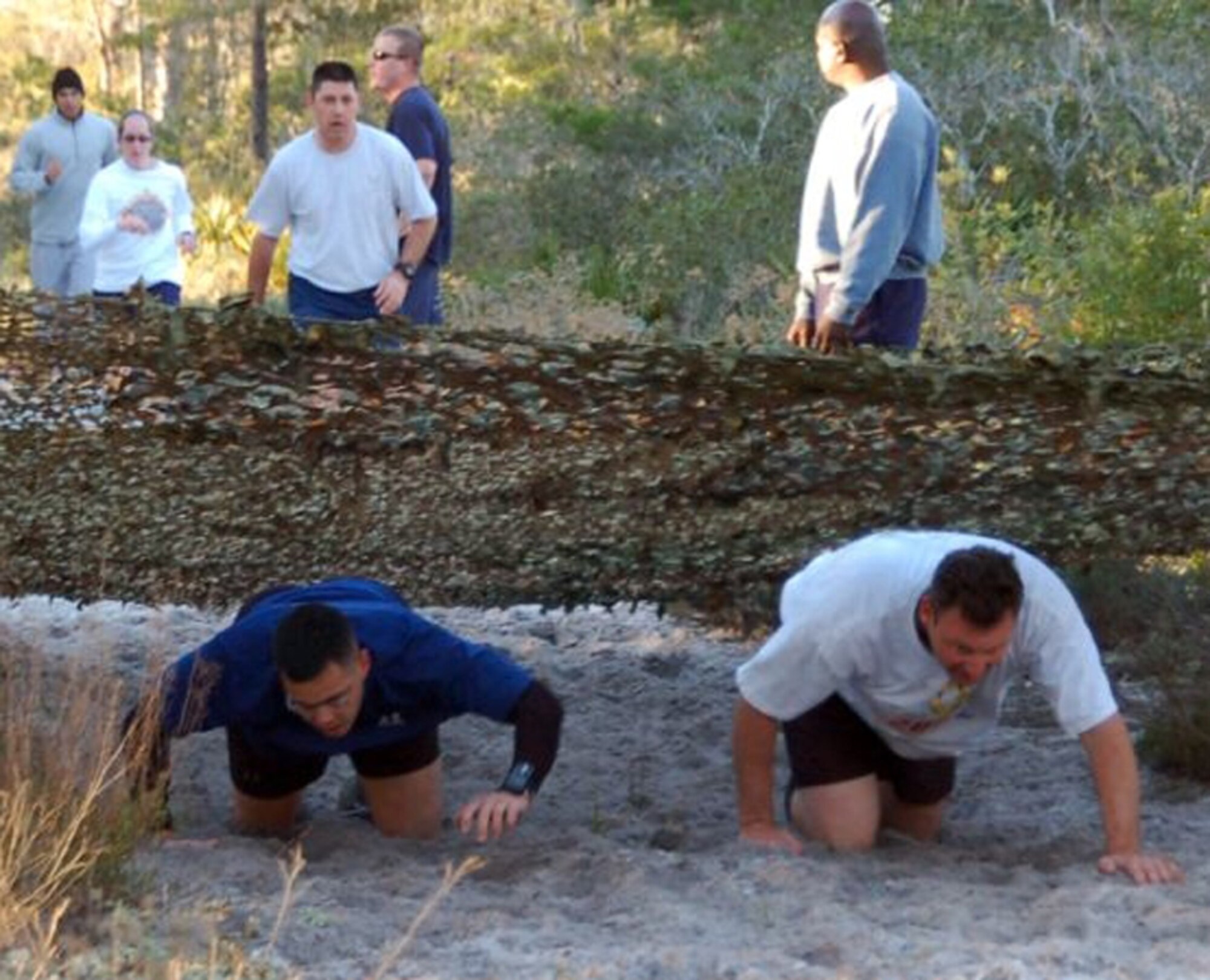 Participants crawl under a tree during the annual Riptide 5K Run Feb. 23. The team event included low crawling under camouflaged netting, skipping through discarded trees, jumping over and crawling through drainage pipes, walking over a plank-covered creek and jumping over a wall. To win, the team had to cross the finish line as a unit. The 20th Special Operations Squadron won first place. (Courtesy photo)