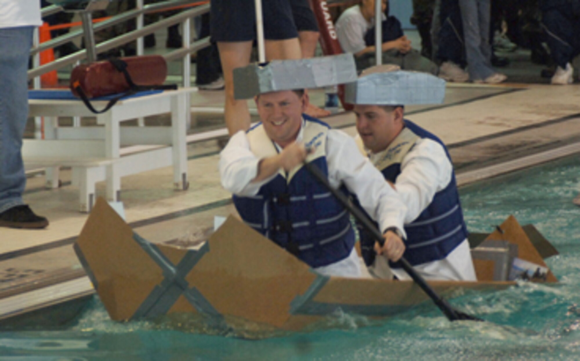 Two boaters dressed as patriots paddle their cardboard boat across the base pool Feb. 23 during the Frosty Sailors race at Winter Bash. (U.S. Air Force photo/Staff Sgt. Suellyn Nuckolls)