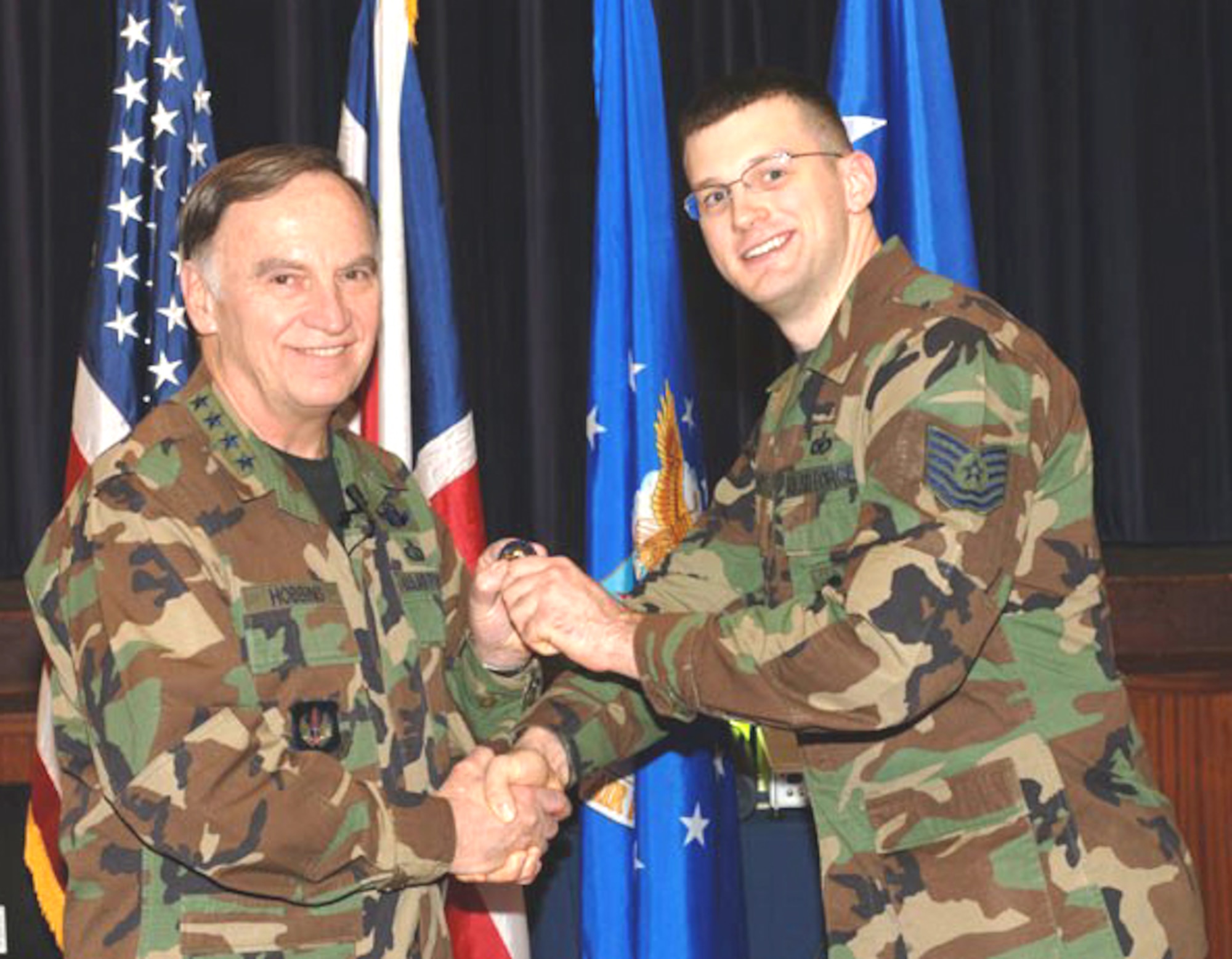 ROYAL AIR FORCE CROUGHTON, England -- Tech. Sgt. Dustin Schimp (right), a member of the 434th Security Forces Squadron, is presented with a special recognition coin by General William T. Hobbins, Commander, United States Air Forces in Europe, for his outstanding job performance.  Sergeant Schimp is deployed to England to provide support to active duty forces.  (U.S. Air Force photo)
