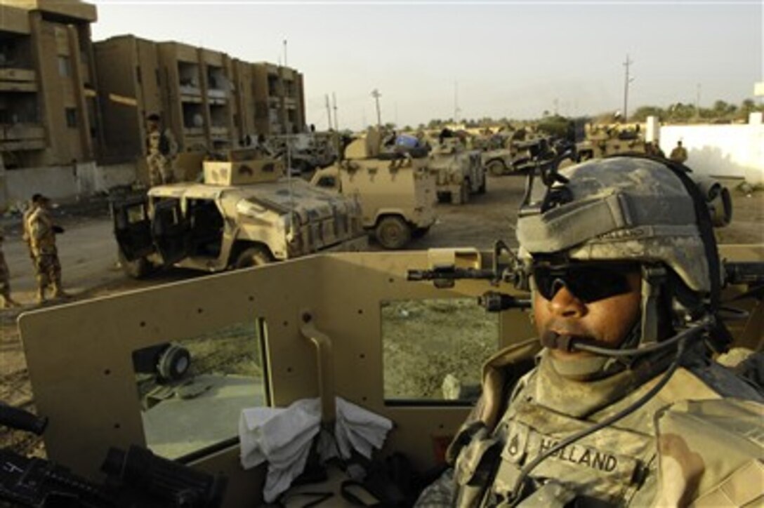 U.S. Army Staff Sgt. Charles Holland with the Military Transition Team provides security from his turret for Iraqi army soldiers with 4th Battalion, 2nd Brigade, 5th Iraqi Army Division, during a raid operation in Tahrir, Iraq, Feb. 27, 2007.