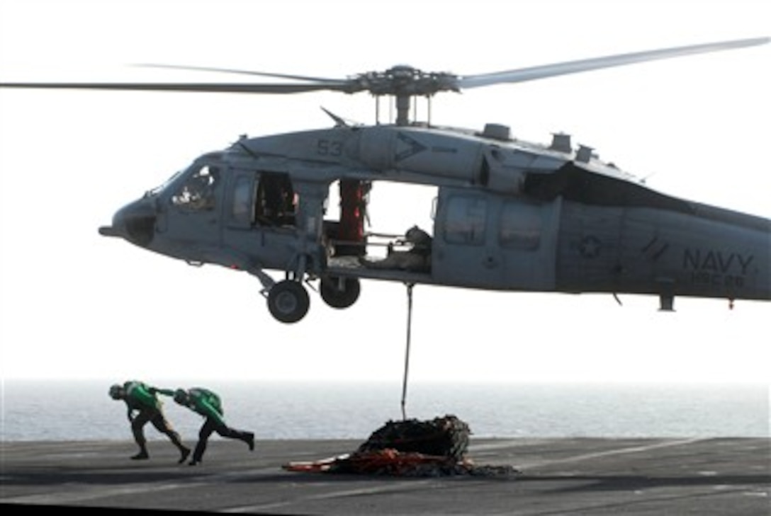 Flight deck crewmen aboard the aircraft carrier USS John C. Stennis (CVN 74) move out after connecting a cargo pendant to an MH-60S Seahawk helicopter during a vertical replenishment with the Military Sealift Command fast combat support ship USNS Arctic (T-AOE 8) while under way in the Arabian Sea on Feb. 28, 2007.  The USS John C. Stennis Carrier Strike Group is deployed in support of maritime security operations in the area.  