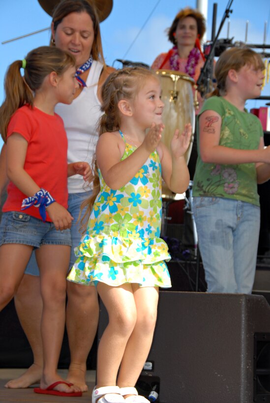Four-year-old Kayla Dow, daughter of Petty Officer 1st Class Peter Dow, Marine Aviation Logistics Squadron 24, claps along to music played by the Lt. Dan Band.  Dow, along with a group of other females, had the opportunity to go on stage during the performance of "Lady Marmalade."