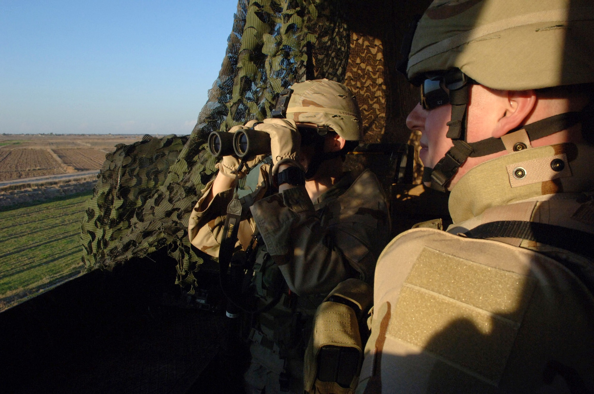 Staff Sgt. Joseph Brown and Airman 1st Class Robert Lisenbee use binoculars to survey their sector from a perimeter guard tower Feb. 19 at Balad Air Base, Iraq. The Airmen are assigned to the 332nd Expeditionary Security Forces Squadron. (U.S. Air Force photo/Staff Sgt. Michael R. Holzworth)