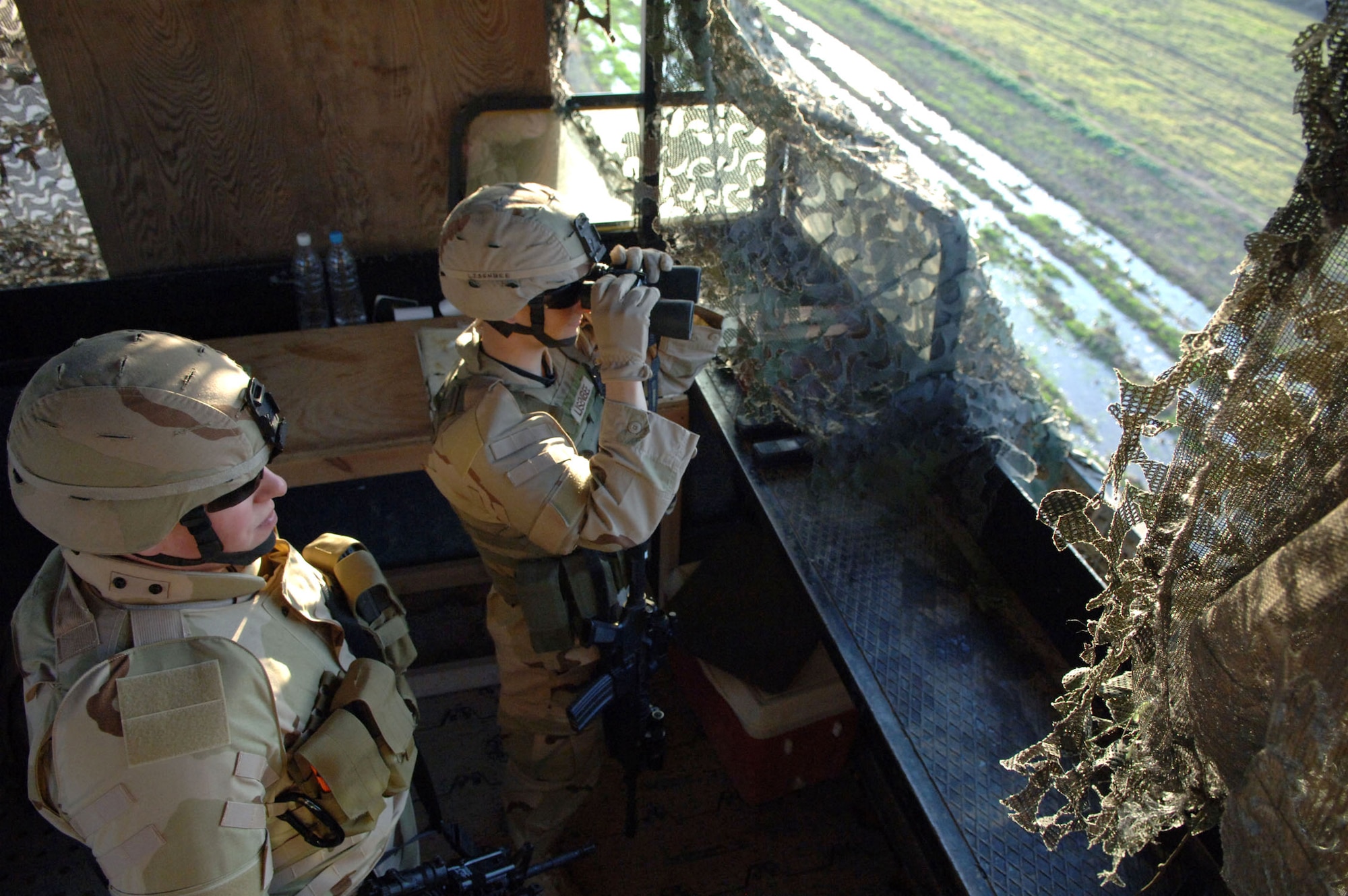 Staff Sgt. Joseph Brown and Airman 1st Class Robert Lisenbee use binoculars to survey their sector from a perimeter guard tower at Balad Air Base, Iraq, Feb. 19. The Airmen are assigned to the 332nd Expeditionary Security Forces Squadron. (U.S. Air Force photo/Staff Sgt. Michael R. Holzworth)