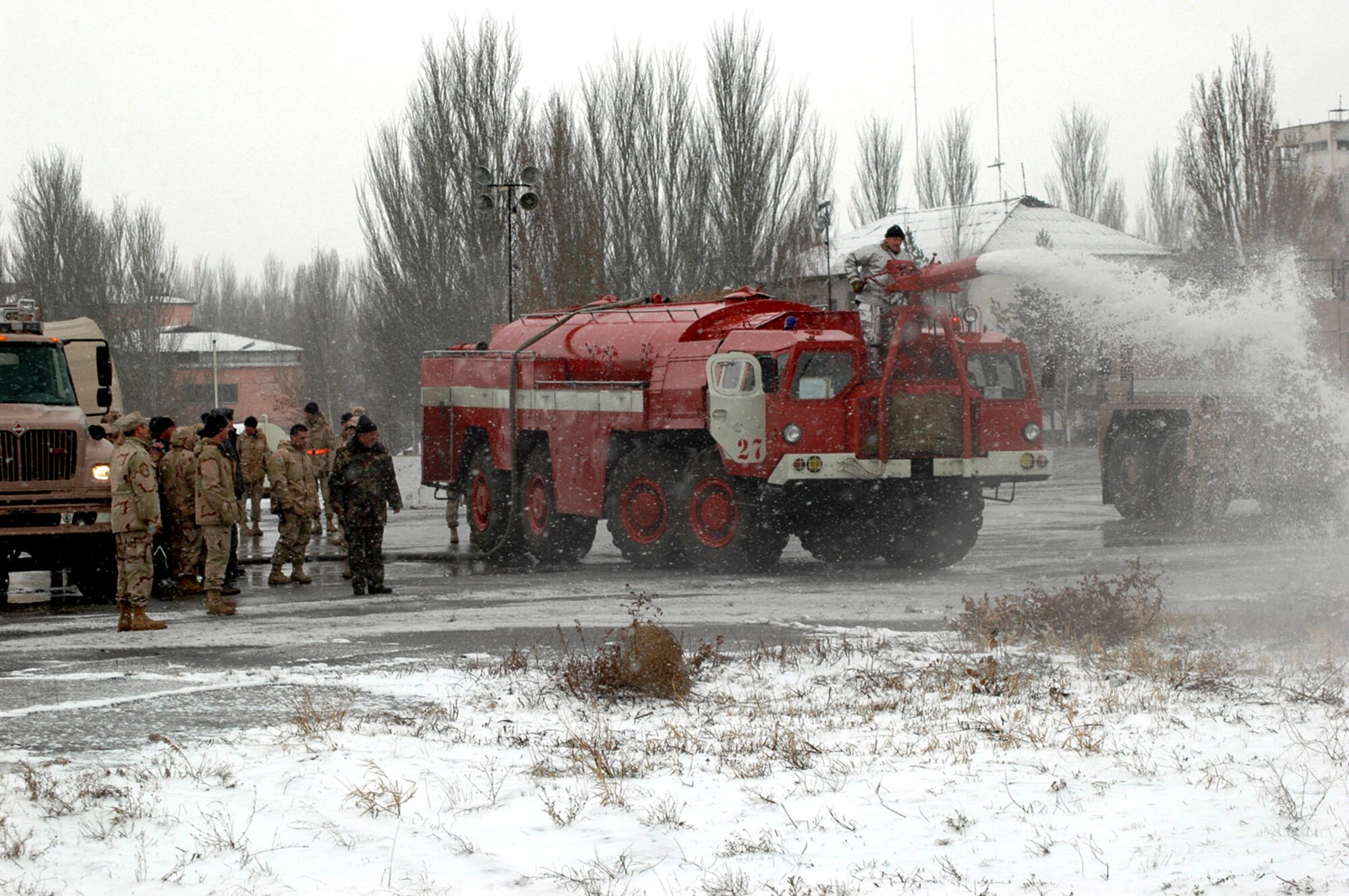 Manas International Airport firefighter Stas Suleymanov demonstrates to Airmen the use of the Kyrgyz firetruck water canon using water pumped from a 376th Air Expeditionary Wing fire truck Feb. 25 at the airport in Kyrgyzstan. The 376th AEW fire department routinely trains with their MIA and other Kyrgyz counterparts. (U.S. Air Force photo/Master Sgt. Daniel Nathaniel) 