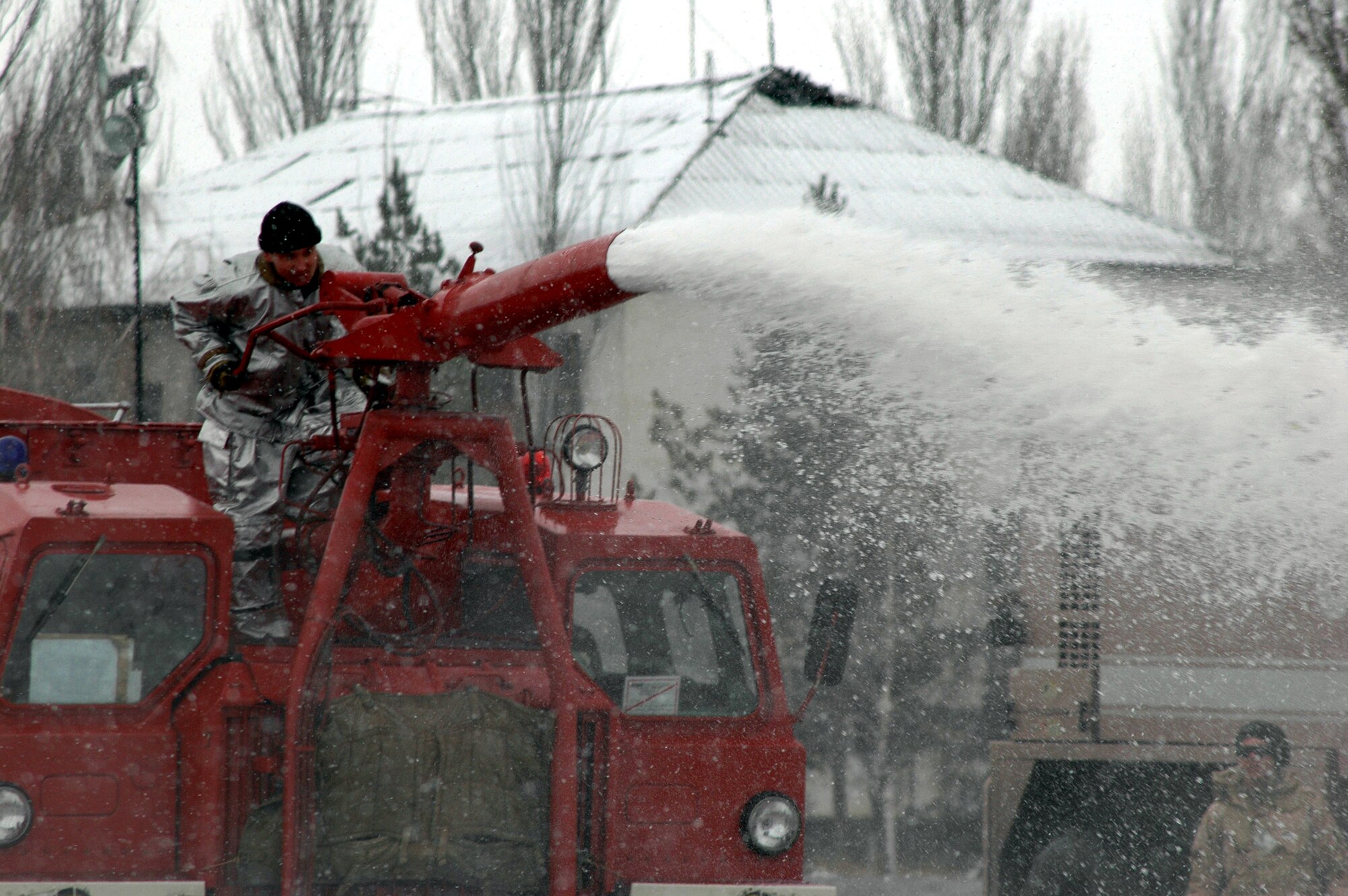 Manas International Airport firefighter Stas Suleymanov demonstrates to Airmen the use of the Kyrgyz firetruck water canon using water pumped from a 376th Air Expeditionary Wing fire truck Feb. 25 at the airport in Kyrgyzstan. The 376th AEW fire department routinely trains with their MIA and other Kyrgyz counterparts. (U.S. Air Force photo/Master Sgt. Daniel Nathaniel) 