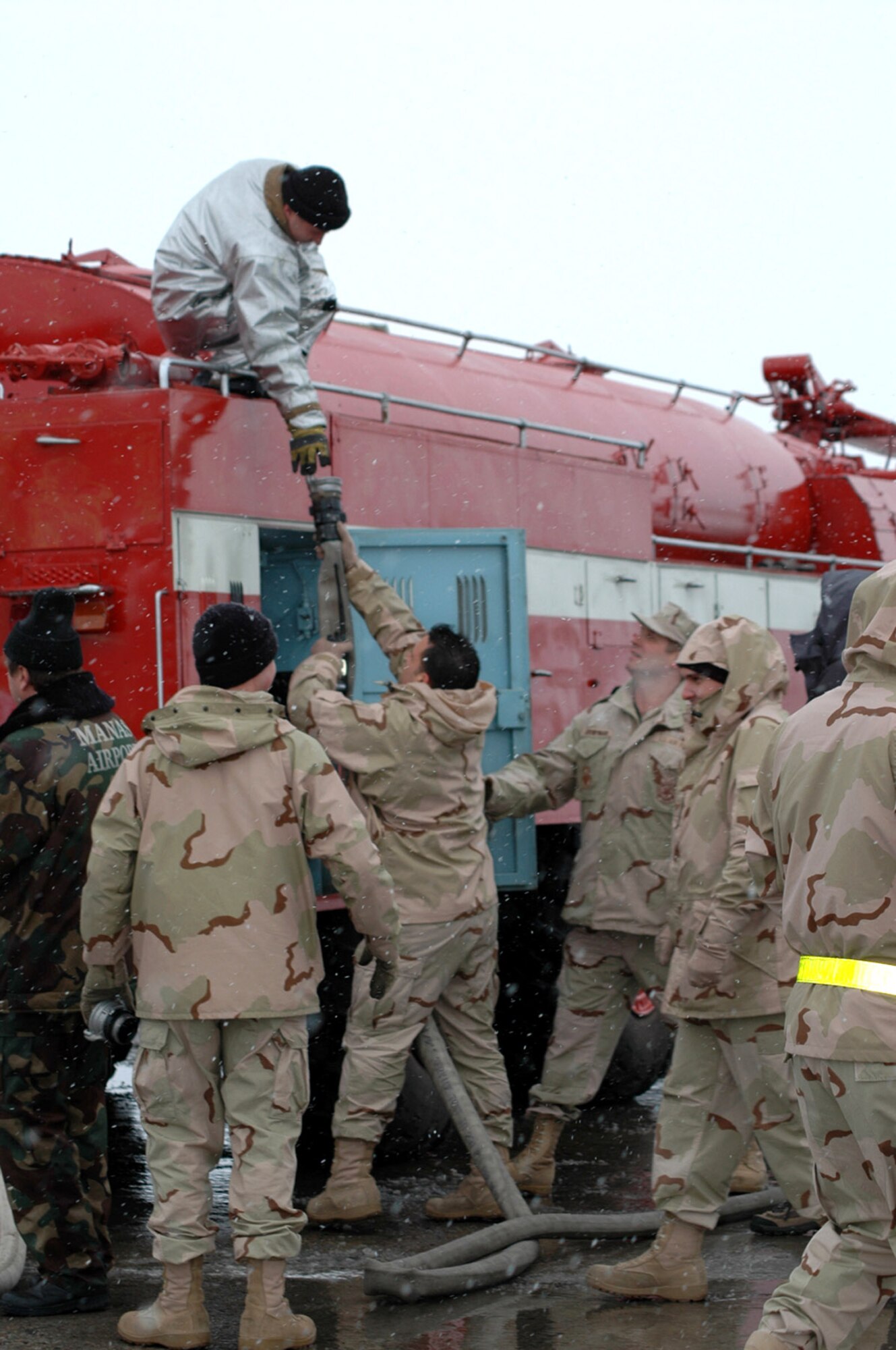 Staff Sgt. Vincent Anselmo hands a fire hose to Stas Suleymanov Feb. 25 at the Manas International Airport in Kyrgyzstan. In this exercise, the Kyrgyz fire truck received water from the 376th Air Expeditionary Wing coalition fire truck. Sergrant Anselmo is a 376th Air Expeditionary Wing firefighter deployed from the 31st Civil Engineer Squadron Fire Deptartment at Aviano Air Base, Italy. Mr. Suleymanov is a firefighter with the Manas International Airport. (U.S. Air Force photo/Master Sgt. Daniel Nathaniel) 