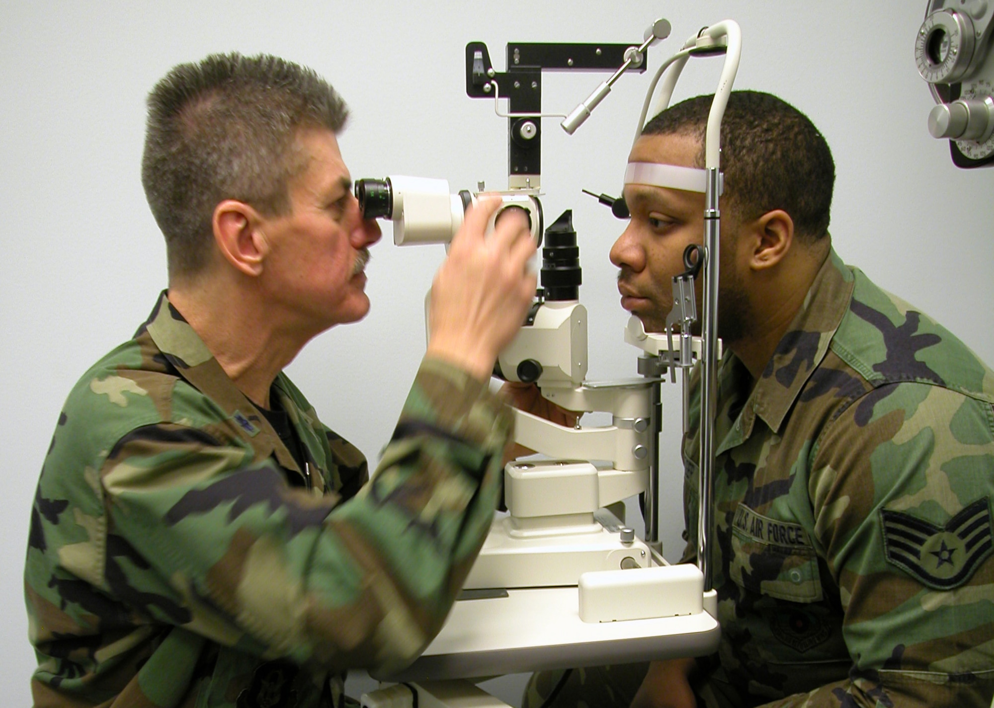 GRISSOM AIR RESERVE BASE, Ind., --  Lt. Col. (Dr.) Ricardo Salvat, an optometrist with the 434 Aerospace Medicine Squadron, demonstrates how the slit-lamp is used to view corneal abrasions on the eye.  The instrument shines a blue light on the eye of Staff Sgt. Jason Geiger, an optometry technician with the 434th AMDS.  This light will show any imperfections on the eye that might cause vision problems.  A florescent dye is used in the patient?s eye to illuminate the abrasions. (Air Force photo / SrA. Ben Mota)