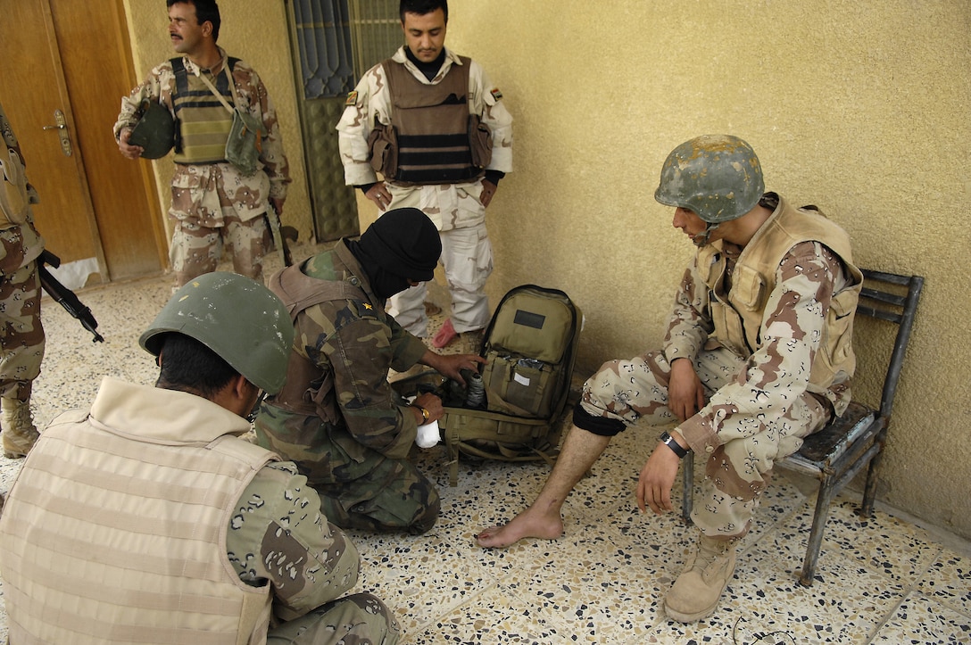 An Iraqi army medic, assigned to the 4th Battalion, 2nd Brigade, 5th Division, provides treatment for a soldier, who got shot in the toe, during Operation Brown Hawk in Tahrir, Iraq, on Feb. 25, 2007.