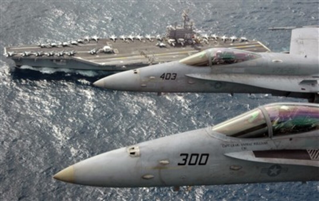 Flying F/A-18C Hornets above the USS Ronald Reagan, Capt. Craig Williams, foreground, and Capt. Richard Butler look up for a photo during their airborne change of command ceremony, March 1, 2007. Butler, a University of Kentucky graduate with more than 21 years of experience as a naval aviator, relieved Williams as the commander of Carrier Air Wing 14.