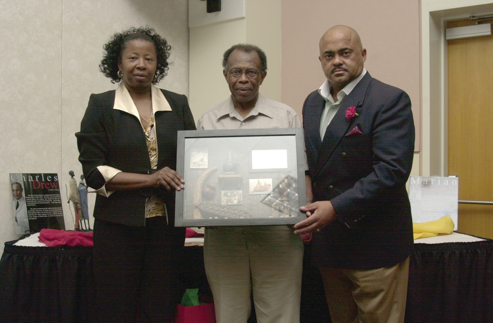 Karen Mitchell (left) and Master Sgt. David Bryan present Wendell Johnson (Center) with a gift as token of appreciation for Mr. Johnson’s more than 40 years of service to Goodfellow and his extensive participation in the base’s African-American Heritage Committee. (U.S. Air Force photo by Airman 1st Class Luis Loza Gutierrez)