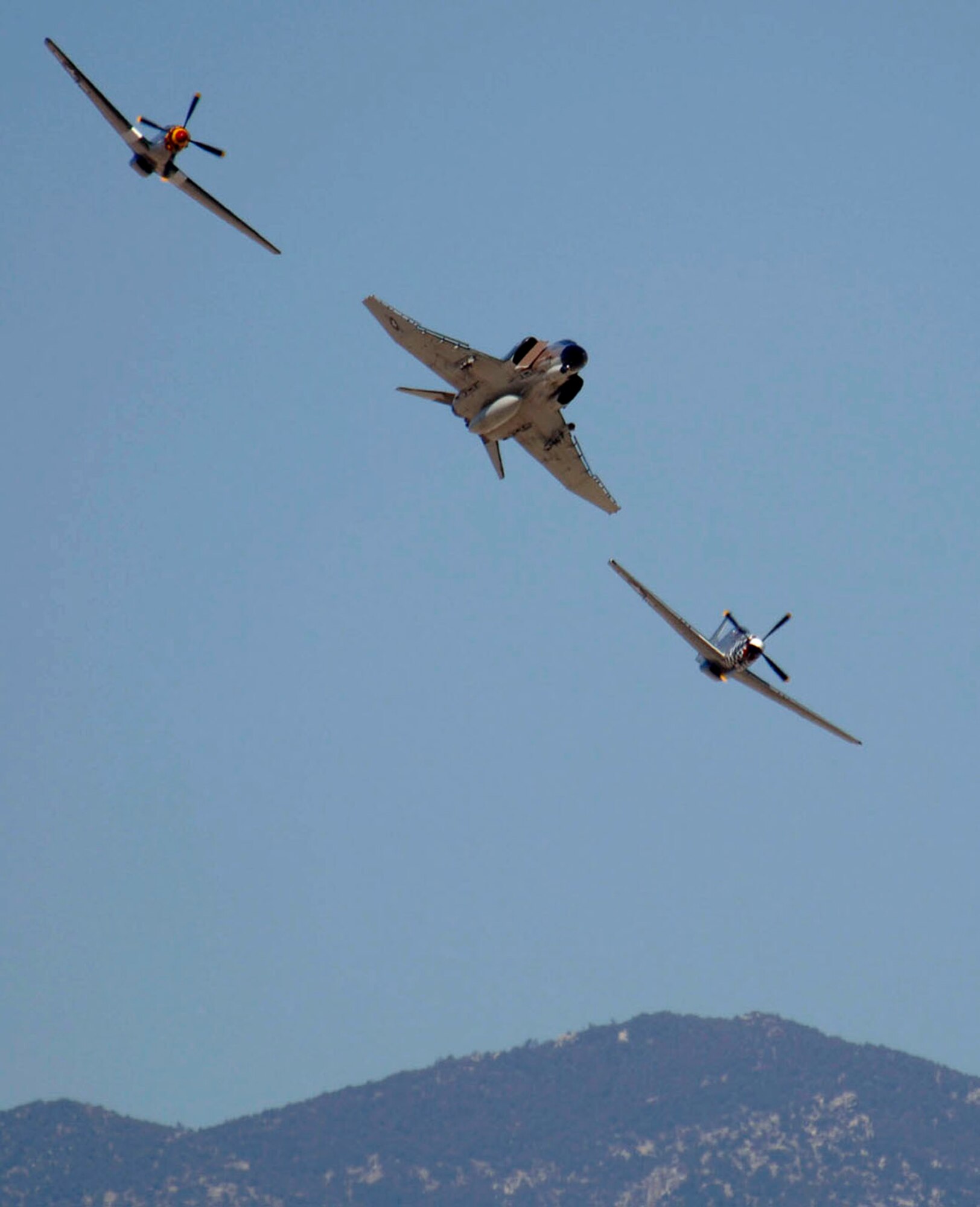 Two P-51 Mustangs flank an F-4 Phantom II while demonstrating aerial capabilities March 3 during the 2007 Heritage Conference at Davis-Monthan Air Force Base, Ariz.  The conference provides an opportunity for ACC demonstration pilots to train together with modern and historic military aircraft in preparation for the upcoming air-show season.   (U.S. Air Force photo/Senior Airman Christina D. Ponte)