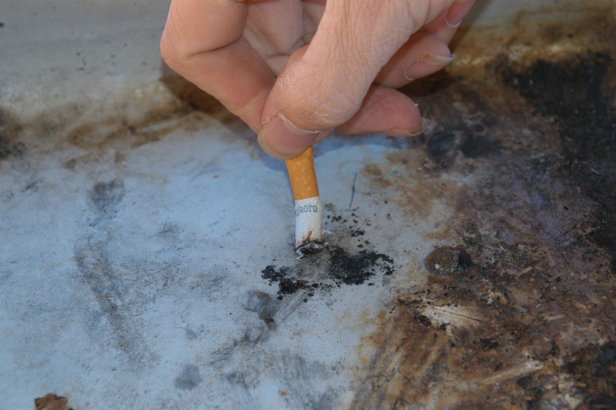 Airman 1st Class Mitchell Yager, 7th Comptroller Squadron, extinguishes a cigarette in a designated smoking area on base March 5. Airman Yager is one of the many Airmen who lives in the dormitories who will be affected by the tobacco ban that will take effect March 7. (U.S. Air Force photo by Airman 1st Class Carolyn Viss)