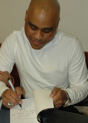 Wing member, playwright and book author Bruce Johnson signs a copy of his latest book, "The Many Faces of Katrina" during a book signing Tuesday, Feb. 27, at Barksdale's base theater . Bruce co-authored this book, telling personal accounts of Katrina survivors, with Toni Tanner Castillo, a friend and co-worker. (U.S. Air Force photo/Tech. Sgt. Sherri Bohannon)
