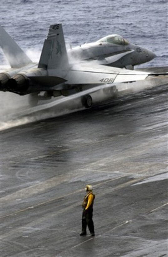 A flight deck crewman watches as a U.S. Navy F/A-18C Hornet aircraft takes off from the aircraft carrier USS Ronald Reagan (CVN 76) as the ship operates in the East China Sea on March 5, 2007.  The Ronald Reagan Carrier Strike Group and Carrier Air Wing 14 are on a surge deployment in support of U.S. military operations in the Western Pacific Ocean.  