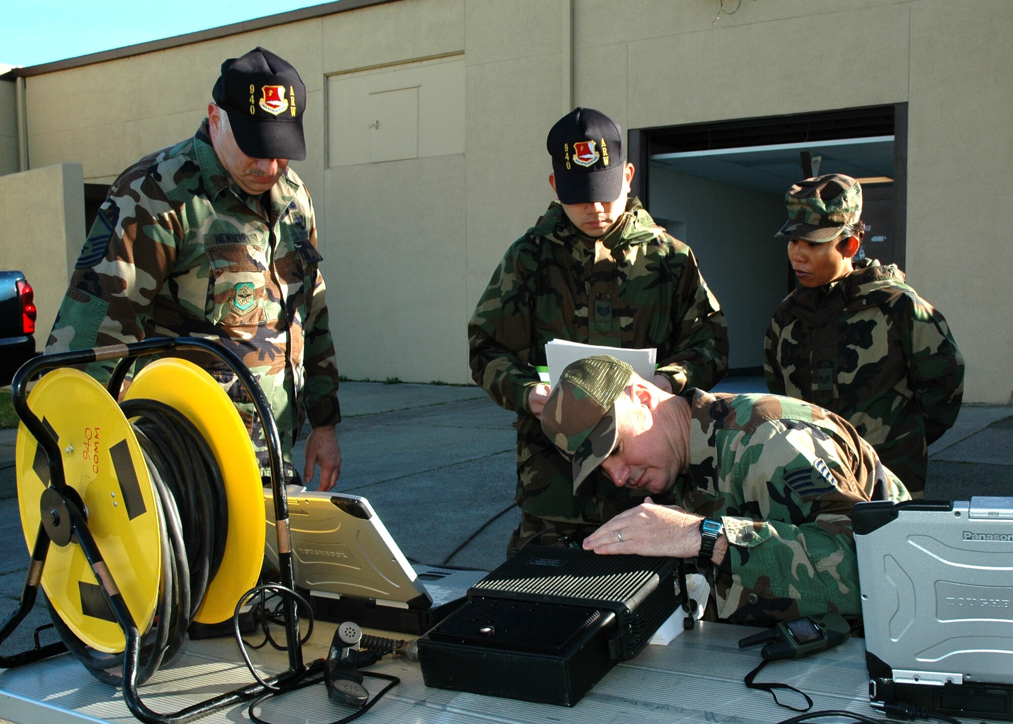 Air Force Reservist Staff Sgt. Troy Surratt (lower right), 940th Communications Flight secure communications specialist, establishes a satellite communication link during training March 3, 2007 at Beale Air Force Base, Calif.  While Sergeant Surratt prepares the radio, Master Sgt. David Newberry, ground radio technician, and Tech Sgt. David Salvador, a secure communications specialist, both with the 940th CF and Staff Sgt. Phetsamone Bouthsarath, 940th Operations Support Flight radio operations specialist, observe the training.  The satellite radio equipment provides both secure and unsecure voice and data capability. (U.S. Air Force photo/Stacey Knott)
