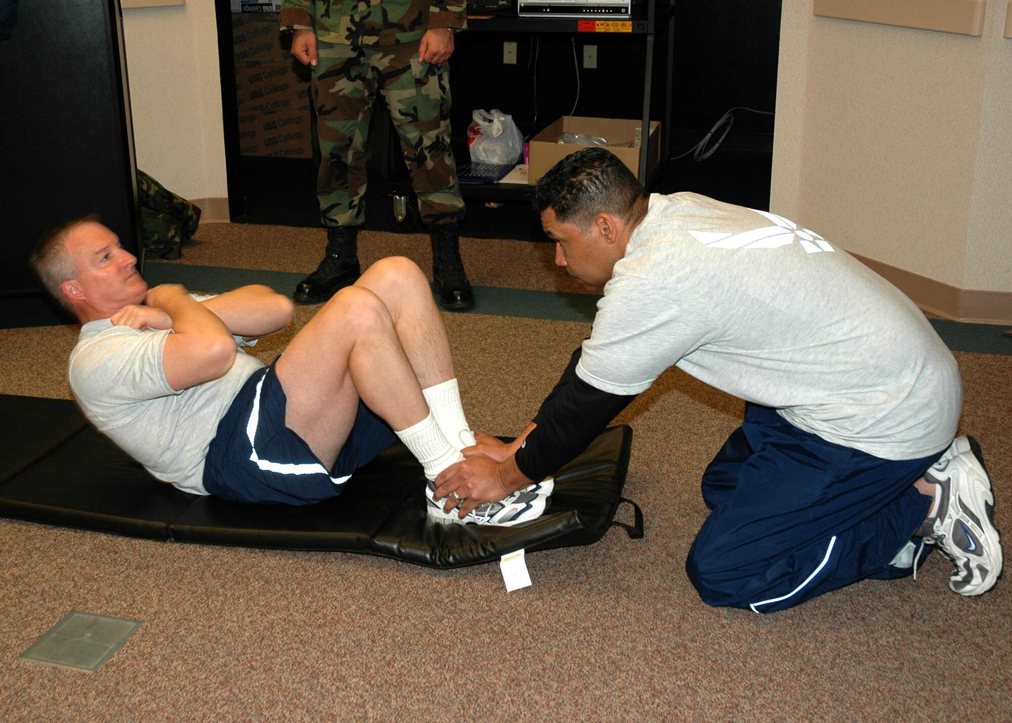 Air Force Reservist Lt. Col. Tim McCoy, 940th Mission Support Group deputy commander, does crunches while Chief Master Sgt. Anthony Armstrong, 940th Air Refueling Wing command chief, provides support during official fitness testing March 4, 2007 at Beale Air Force Base, Calif.  The Air Force physical fitness assessment measures aerobic fitness, physical strength/endurance and body composition and helps ensure Airmen are "Fit to Fight." (U.S. Air Force photo/Stacey Knott)