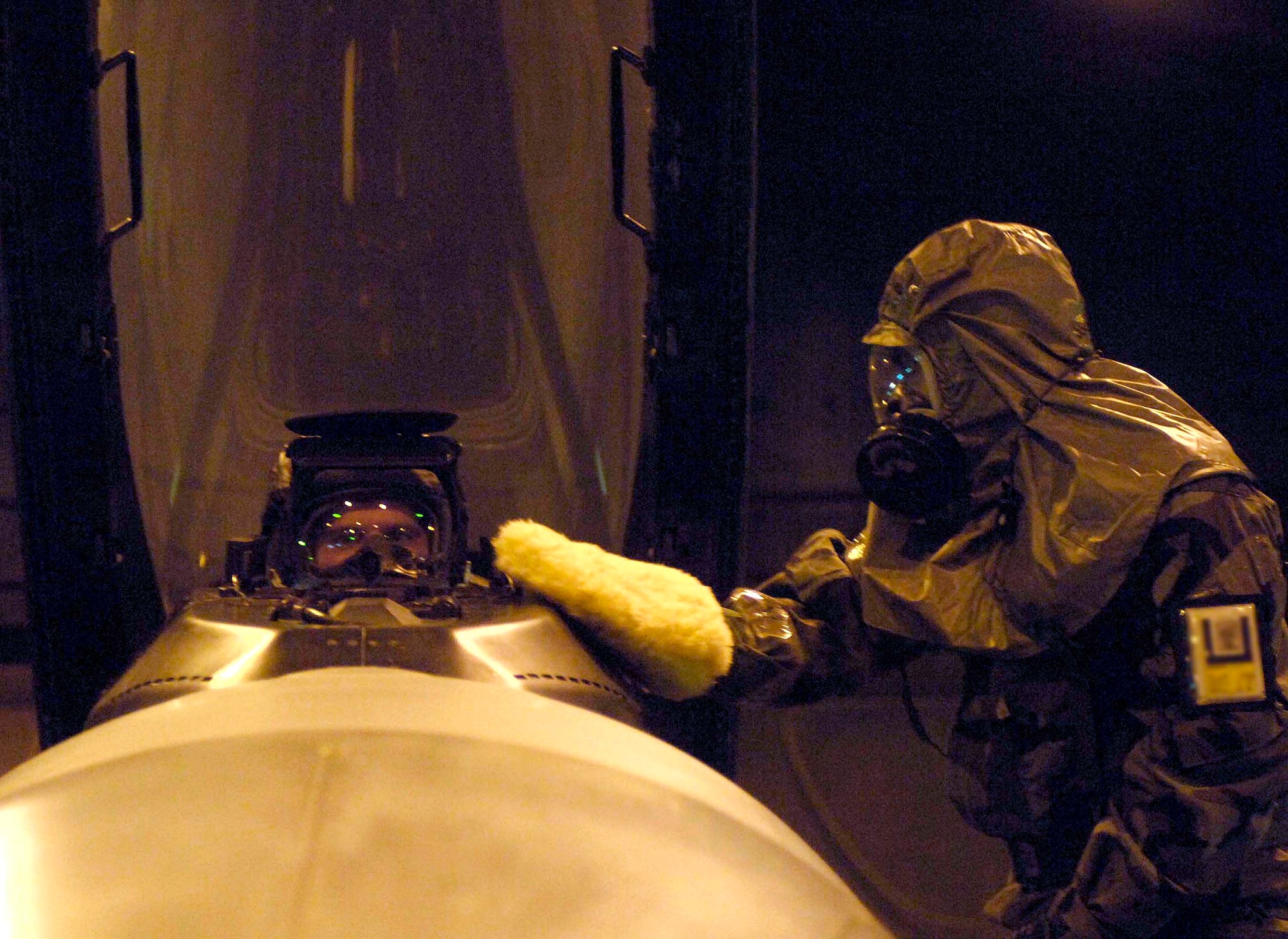 Staff Sgt Brandon Ward uses specially treated mitt March 6 to decontaminate an F-16 Fighting Falcon while the pilot, Capt Derrick Franck, waits to exit the aircraft during a NATO Tactical Evaluation at Aviano Air Base, Italy.  The evaluation is to determine if Aviano's 31st Fighter Wing is prepared to support NATO Response Force 9/10.  (U.S. Air Force photo/Airman 1st Class Michael S. Dorus)