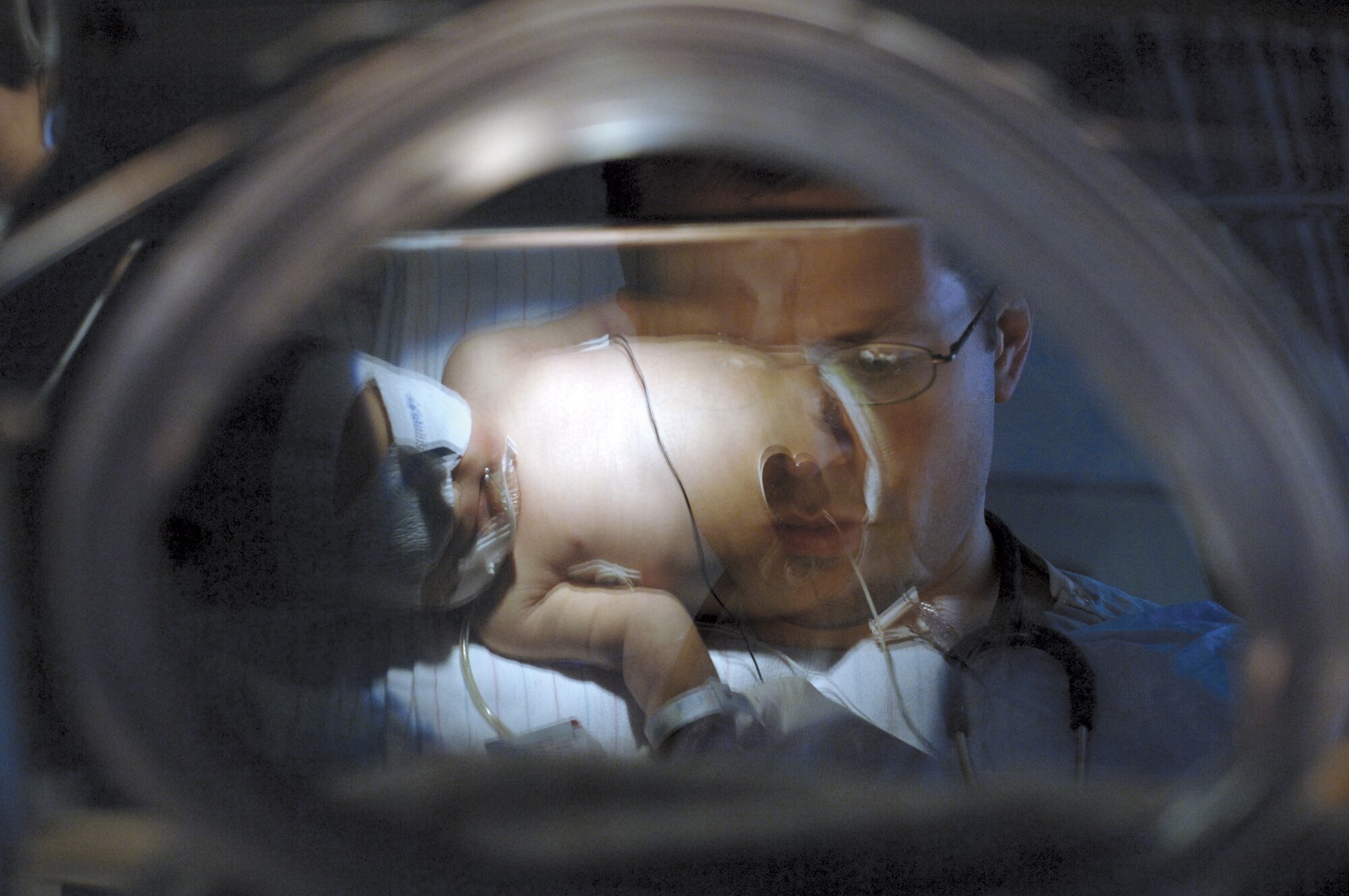 Army Dr. (Capt.) Preston Omer reaches into an isolette, a Plexiglass crib, to draw blood from one of his tiny patients at Wilford Hall Medical Center, Lackland Air Force Base, Texas. (U.S. Air Force photo by Master  Sgt. Ken Wright)