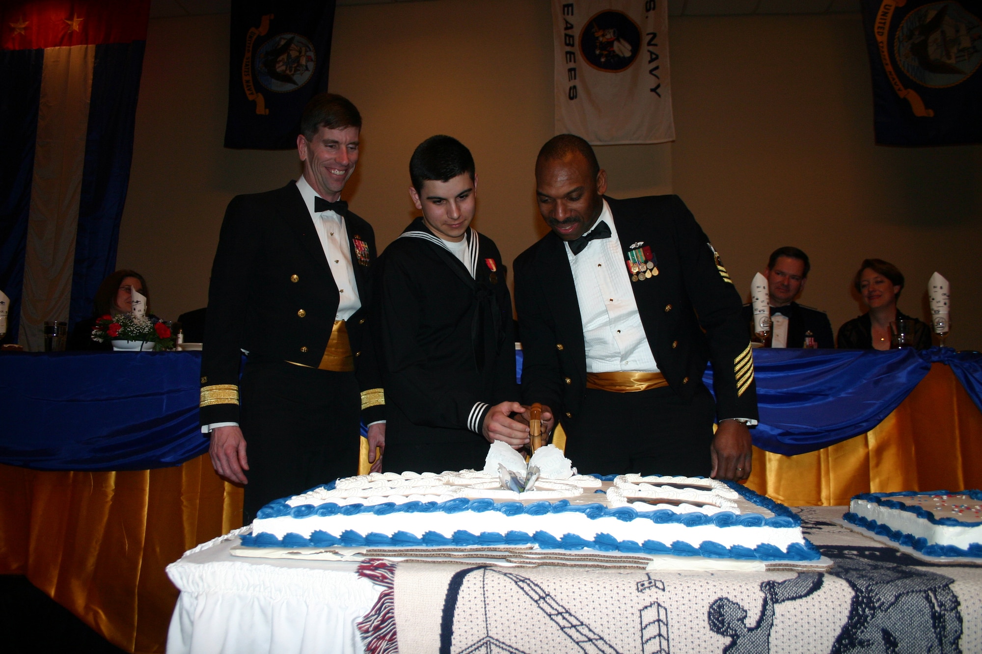 Navy Rear Admiral Mark Handley observes as Seaman Alex Spears and Senior Chief Petty Officer Todd Bolden, the youngest and oldest Seabees in attendance, cut the cake during the Seabee Ball at the Howard Johnson Plaza Hotel March 3. (U.S. Air Force photo/Staff Sgt. Tonnette Thompson)