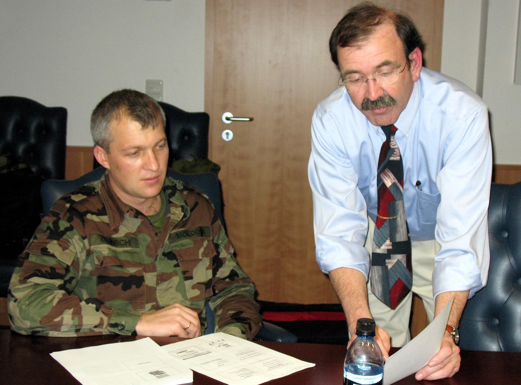 Milan Christi, with the United States Air Forces in Europe personnel office at Ramstein Air Base, Germany, briefs Lt. Colonel Sergiu Ocinschi, a Moldovan army communications officer, about the role of contractors in the Air Force.  Colonel Ocinschi and three other officers from Moldova visited Ramstein to learn about the U.S. Air Force human resources program since their country's military is currently undergoing changes. (U.S. Air Force photo/Staff Sgt. Laura Holzer) 