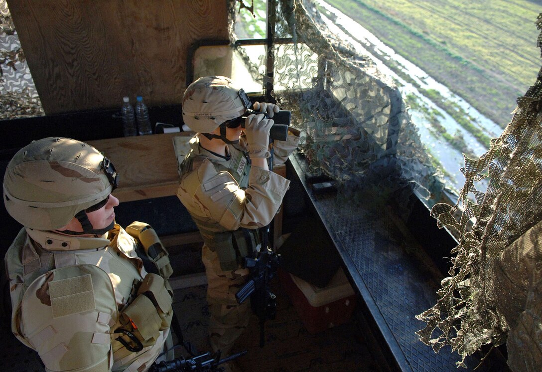 U.S. Air Force Staff Sgt. Joseph Brown and Airman 1st Class Robert Lisenbee survey their sector from a perimeter guard tower at Balad Air Base, Iraq, Feb. 19, 2007.