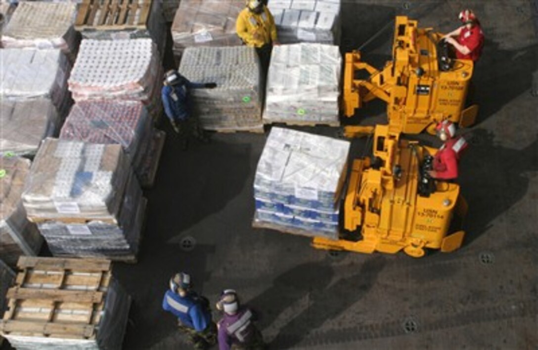 U.S. Navy crew members aboard amphibious assault ship USS Bataan move pallets of food into the ship's hangar bay during a replenishment at sea, March 3, 2007. The Bataan Strike Group is supporting maritime security operations in the U.S. Naval Forces Central Command area of operations.