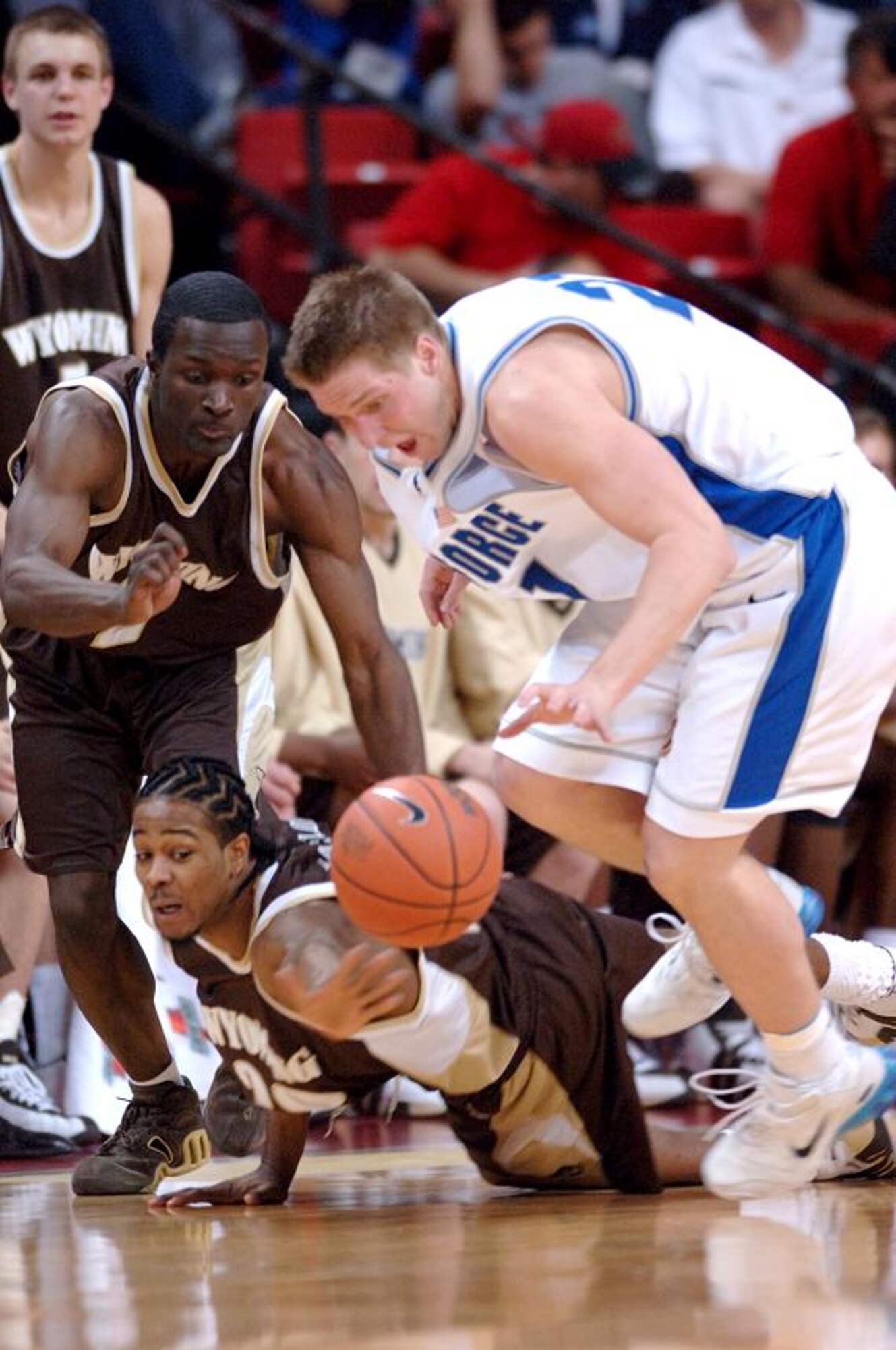 Air Force forward Jacob Burtschi and Wyoming players James Spencer and Joseph Taylor chase a loose ball in their quarterfinal game at the Mountain West Conference tournament in Las Vegas Thursday, March 8. Nationally ranked nearly the entire season, the Falcons were eliminated in their first game of the tourney, 67-62. Air Force now has an all-time record of 0-8 in the MWC tournament. (U.S. Air Force photo/1Lt John Ross)