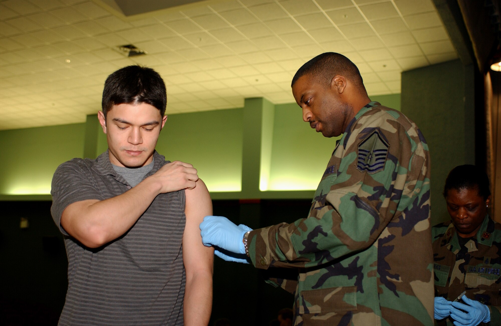 OSAN AIR BASE, Republic of Korea --  Master Sgt. Bruce Mckenzie (right) was one of many people from the 51st Medical Group vaccinating wing and 7th Air Force people at the base theater Wednesday and Thursday. (U.S. Air Force photo by Airman 1st Class Chad Strohmeyer)