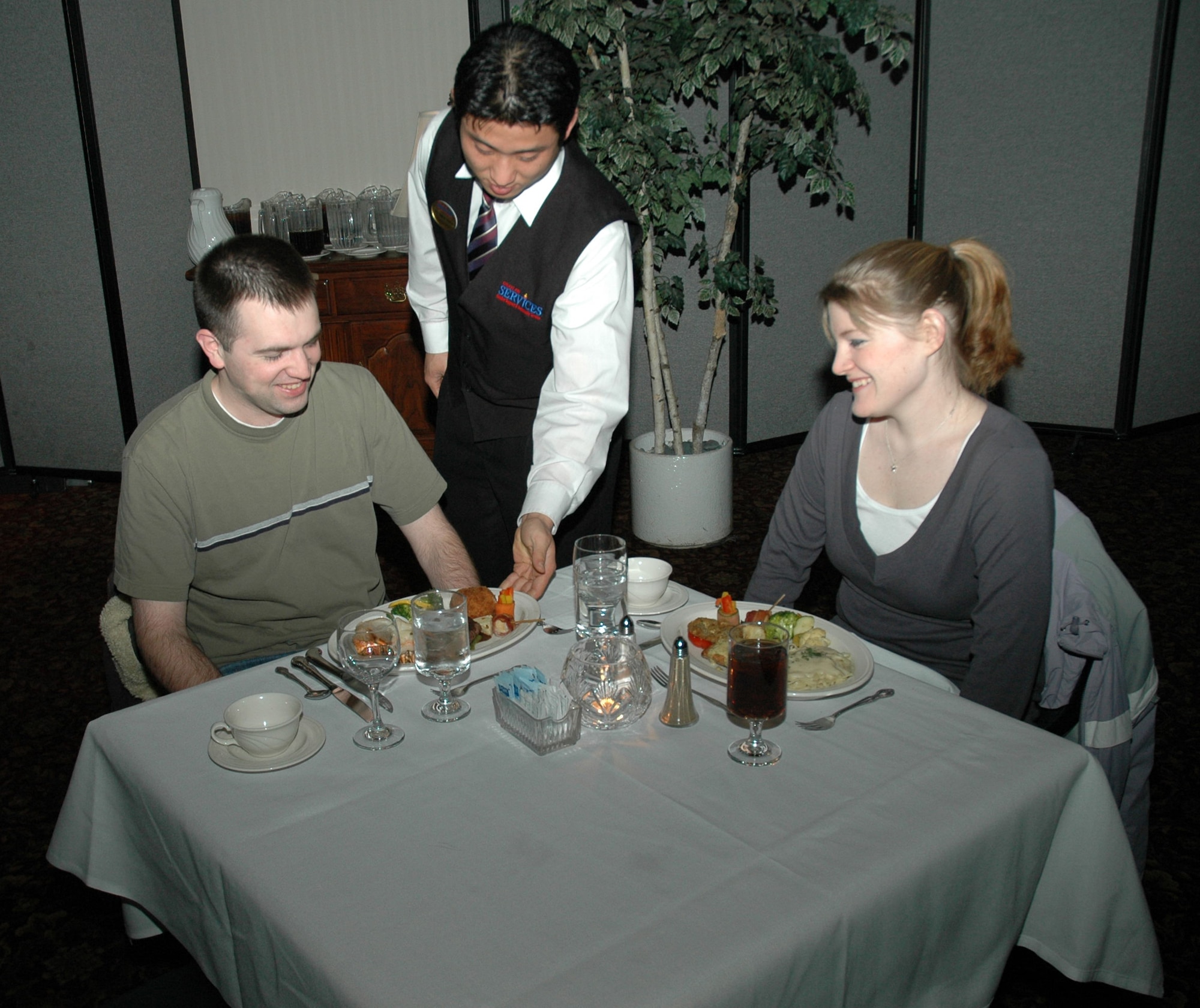 OSAN AIR BASE, Republic of Korea --  Capts. Ross Montante and Lisa Pagano are served their dinner at the Officers’ Club Wine ‘n’ Dine Tuesday. The special is held every Tuesday from 5:30 to 8 p.m. (U.S. Air Force photo by Senior Airman Brok McCarthy)
