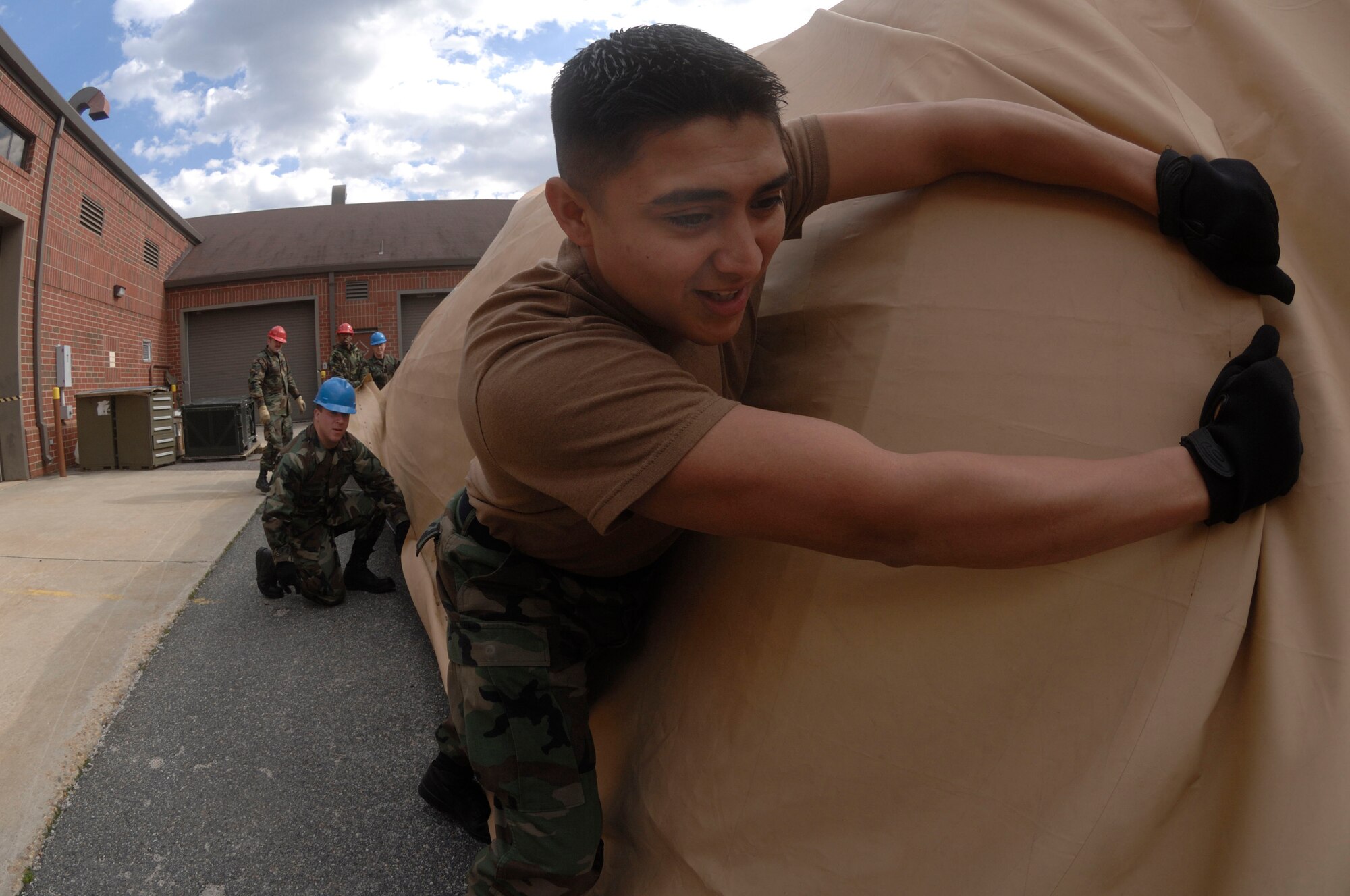 Senior Airman Justin Marroquin, a combat  satellite communications maintenance journeyman assigned to the 1st Communications Squadron, pulls the cover to an Alaskan tent to ensure the cover is in its proper place during the tent set up Feb. 22.  The tent set up is a part of an internal exercise conducted to rate the ability to set up and operate a communications center in a deployed environment. (U.S. Air Force Photo/Staff Sgt. Eric T. Sheler)