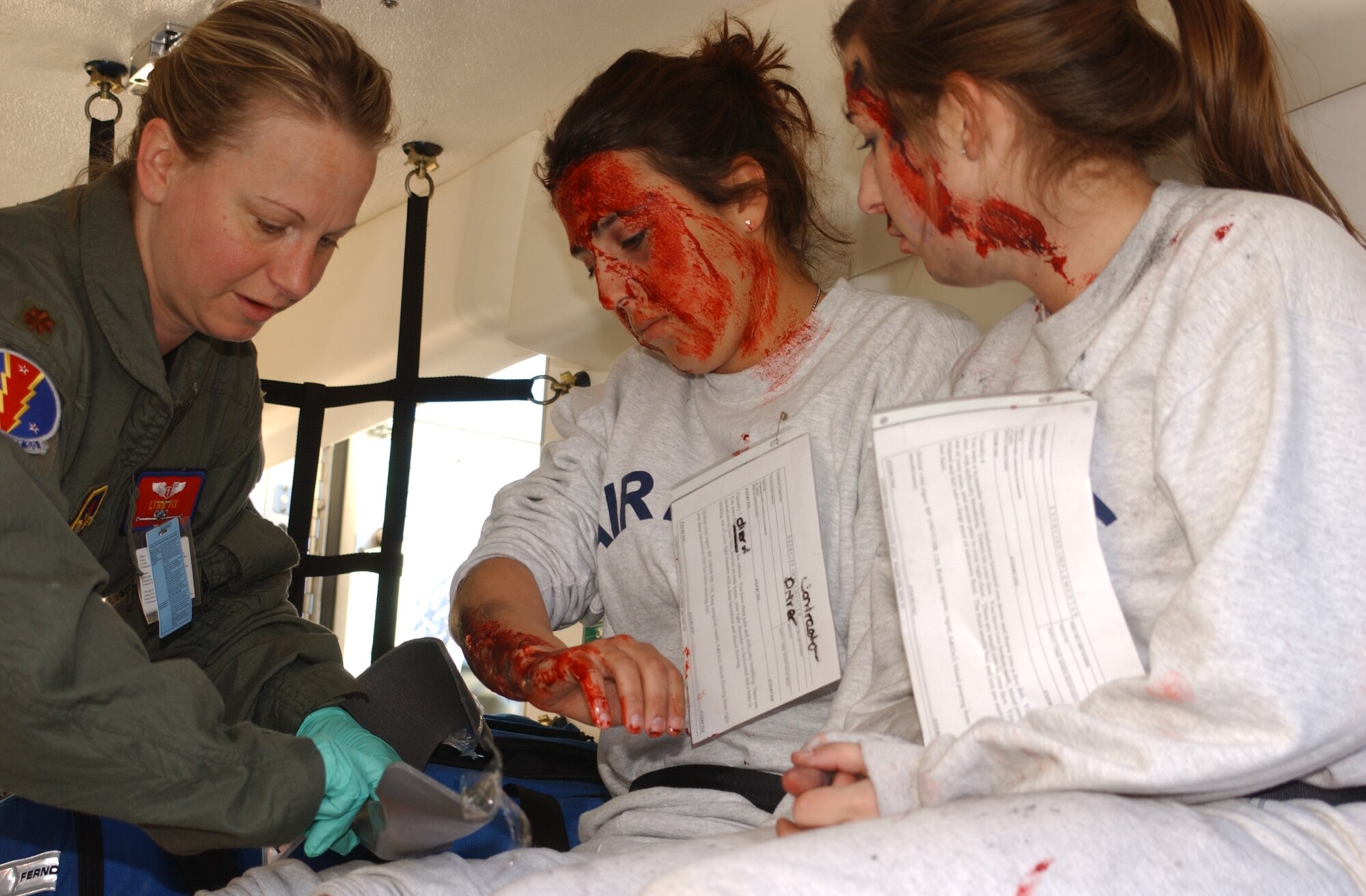 left, Major Lynn Vix, 81 Aerospace Medicine Squadron;  center, Airman Basics Cassie Holmes and Cara Chamberlain, both are students from the 334 Training Squadron.  Vix is treating the airmen’s burns and wounds after being loaded into an ambulance which will transport them to the Keesler Medical Center for more extensive treatment.  They were severly burned and injured in the accident.  Holmes was the driver of the vehicle that was struck by the derailed train,during a major accident response exercise held near the intersection of White Avenue and Irish Hill Rd.  The exercise tested Biloxi and Keesler Air Force Base first-responders' ability to work together in the event of a train derailment.  U.S. Air Force Photo by Kemberly Groue)
