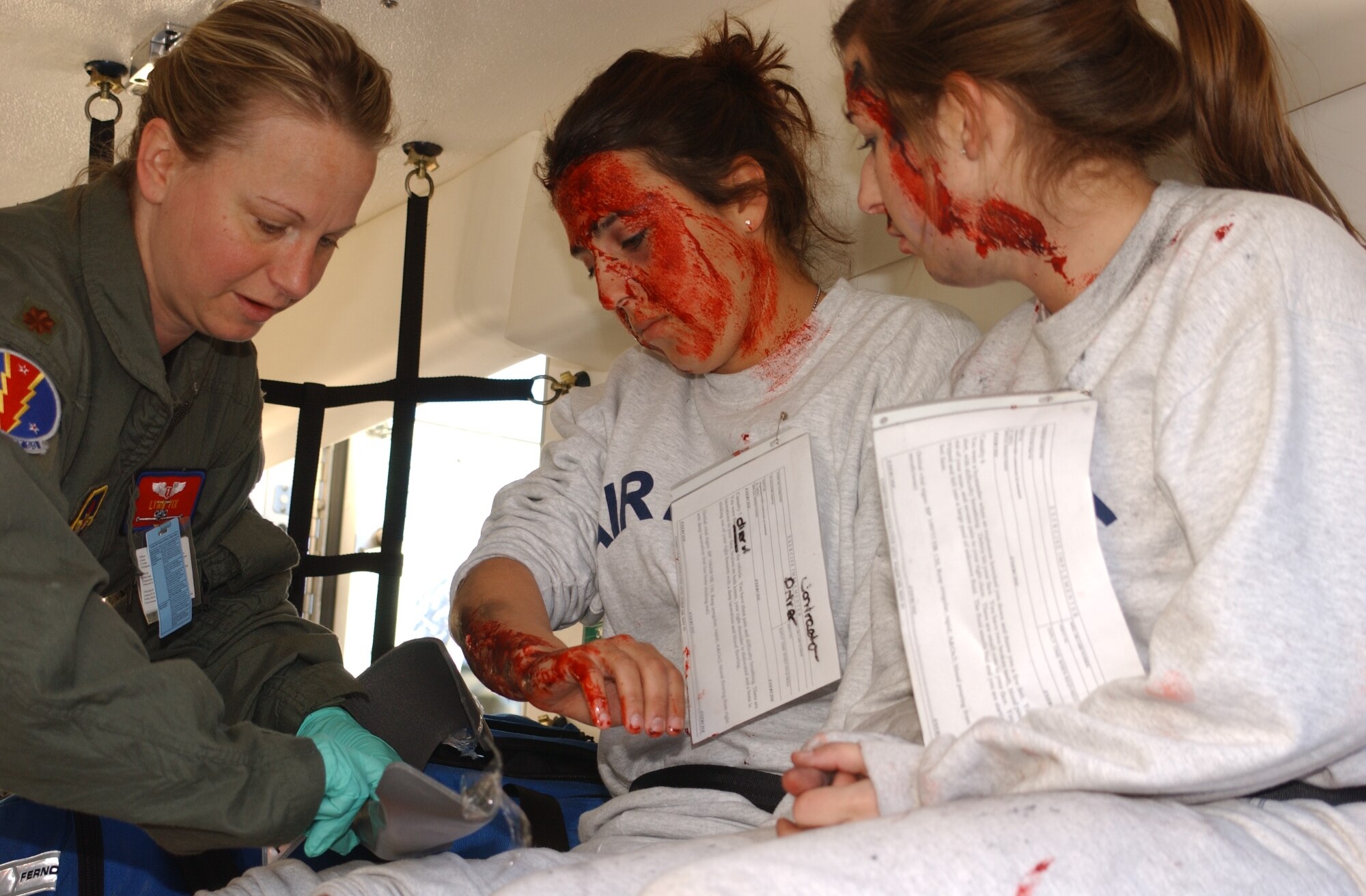 left, Major Lynn Vix, 81 Aerospace Medicine Squadron;  center, Airman Basics Cassie Holmes and Cara Chamberlain, both are students from the 334 Training Squadron.  Vix is treating the airmen’s burns and wounds after being loaded into an ambulance which will transport them to the Keesler Medical Center for more extensive treatment.  They were severly burned and injured in the accident.  Holmes was the driver of the vehicle that was struck by the derailed train,during a major accident response exercise held near the intersection of White Avenue and Irish Hill Rd.  The exercise tested Biloxi and Keesler Air Force Base first-responders' ability to work together in the event of a train derailment.  U.S. Air Force Photo by Kemberly Groue)
