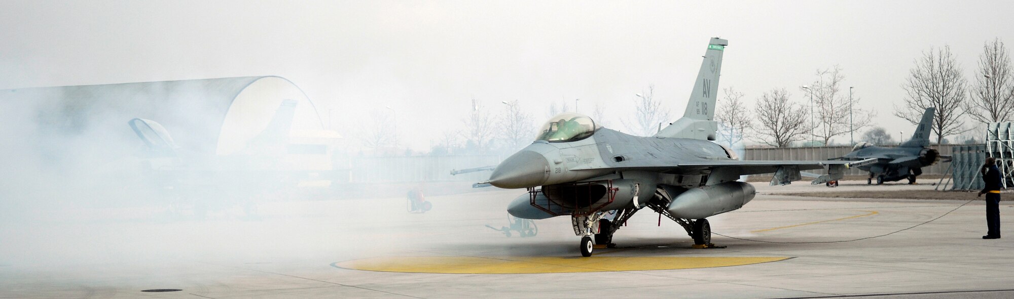 Members of the 31st Aircraft Maintenance Squadron test a newly-installed F-16 engine March 1. The white smoke is created by the agent used to preserve the engine while it is in storage. ( U.S. Air Force photo by Airman 1st Class Michael Dorus)