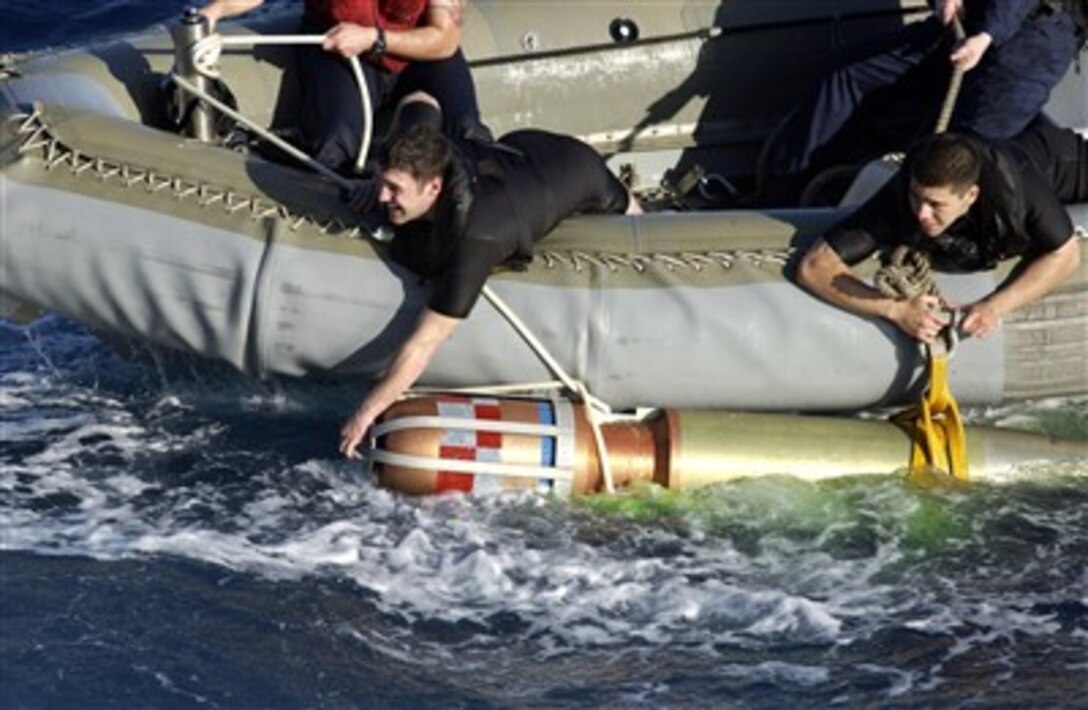 U.S. Navy Quarter Master 2nd Class Christopher P. Whaley (left) and Information Systems Technician 2nd Class Luis Renteria, both rescue swimmers assigned to the guided-missile destroyer USS Mahan (DDG 72) hold onto a training torpedo as they escort it back to the ship. Mahan fired the torpedo during a training exercise in the Atlantic Ocean. 