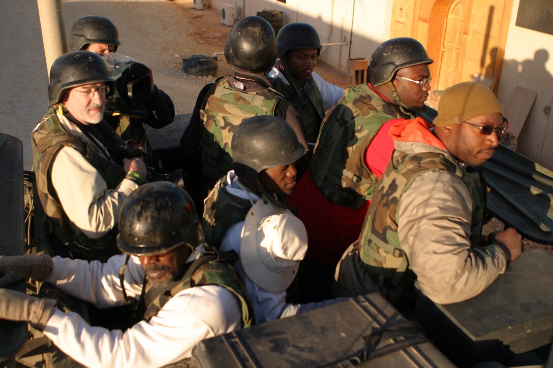 CAMP KOREAN VILLAGE, Iraq (March 8, 2007) -- NFL football players Alge Crumpler, Atlanta Falcons; Shelton Quarles, Tampa Bay Buccaneers; Will Shields, Kansas City Chiefs and Benjamin Watson, New England Patriots ride in a Marine Light Armored Vehicle during a visit to Camp Korean Village, Iraq March 8.  The professional football stars signed autographs and posed for pictures with the Marines and sailors of the 15th Marine Expeditionary Unit (Special Operations Capable).  The players visited several different bases throughout Iraq as part of a tour sponsored by the United Service Organization.  The players were as appreciative of the troops they visited as the troops are for the time the players devoted to visiting Iraq, according to Quarles.  "Everybody has been excited about us being here and been appreciative of us taking our time to come out during the off season.  I'm definitely appreciative of what [the troops] are doing for us, providing our freedom and giving us the opportunity to do what we do," Quarles said..  The 15th MEU (SOC) moved into Rutbah Jan. 20 to provide security and to establish an Iraqi Police force in the city.